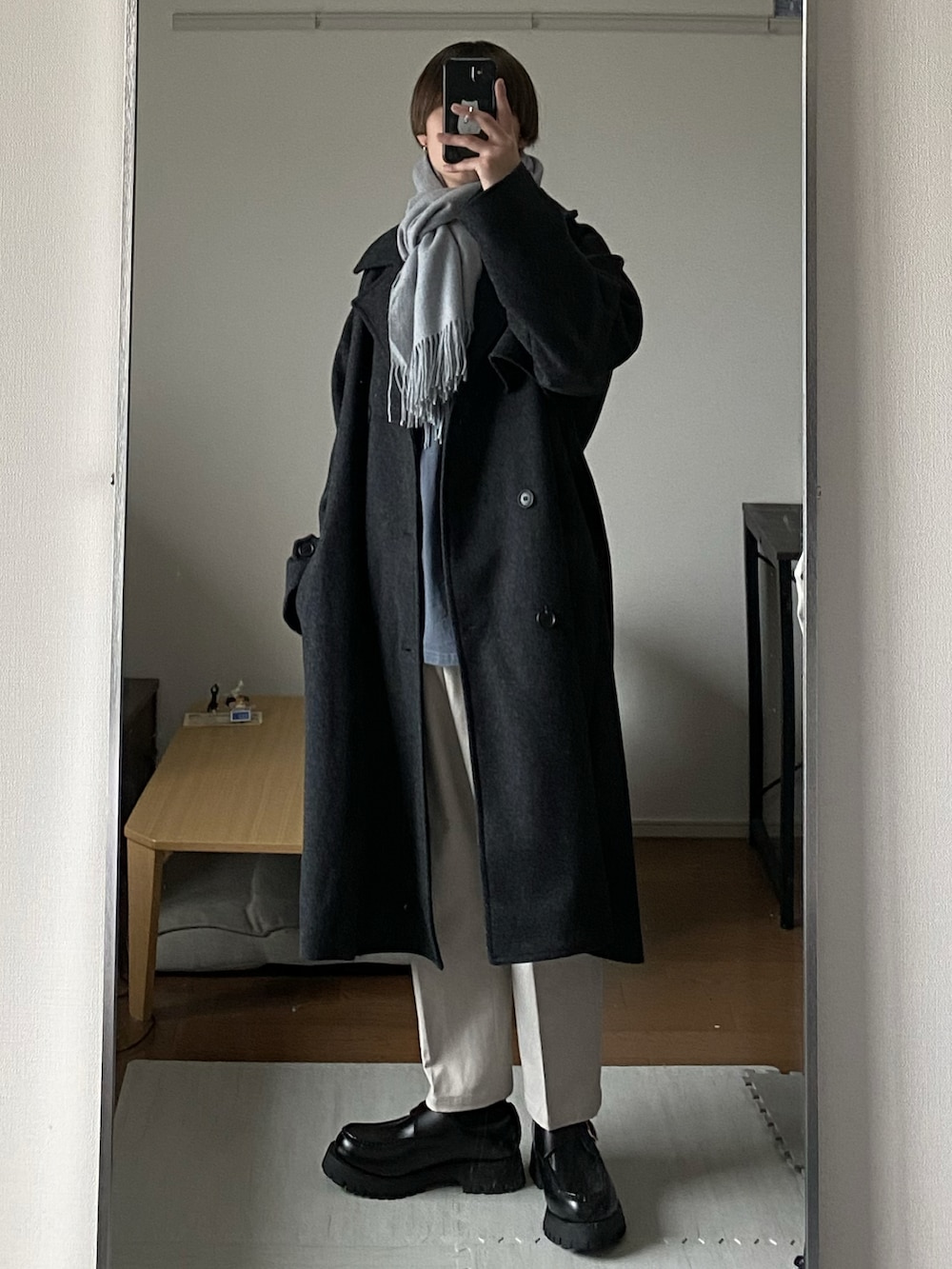 グレー系のトレンチコート、ホワイト系のその他パンツ、ブラック系のローファーを着用したメンズの冬コーディネートの3枚目の写真