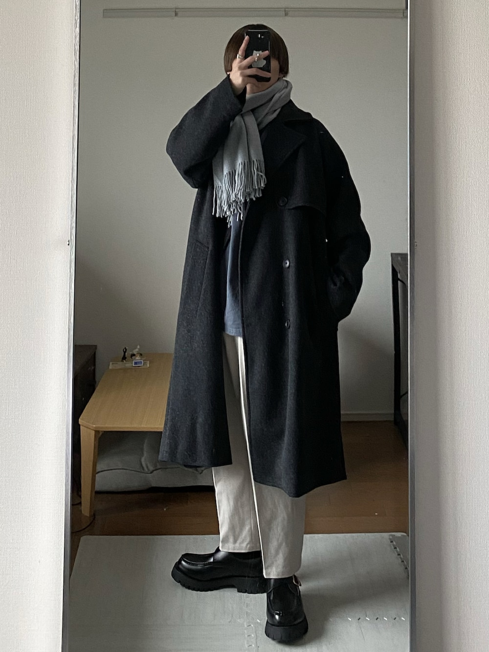 グレー系のトレンチコート、ホワイト系のその他パンツ、ブラック系のローファーを着用したメンズの冬コーディネートの2枚目の写真