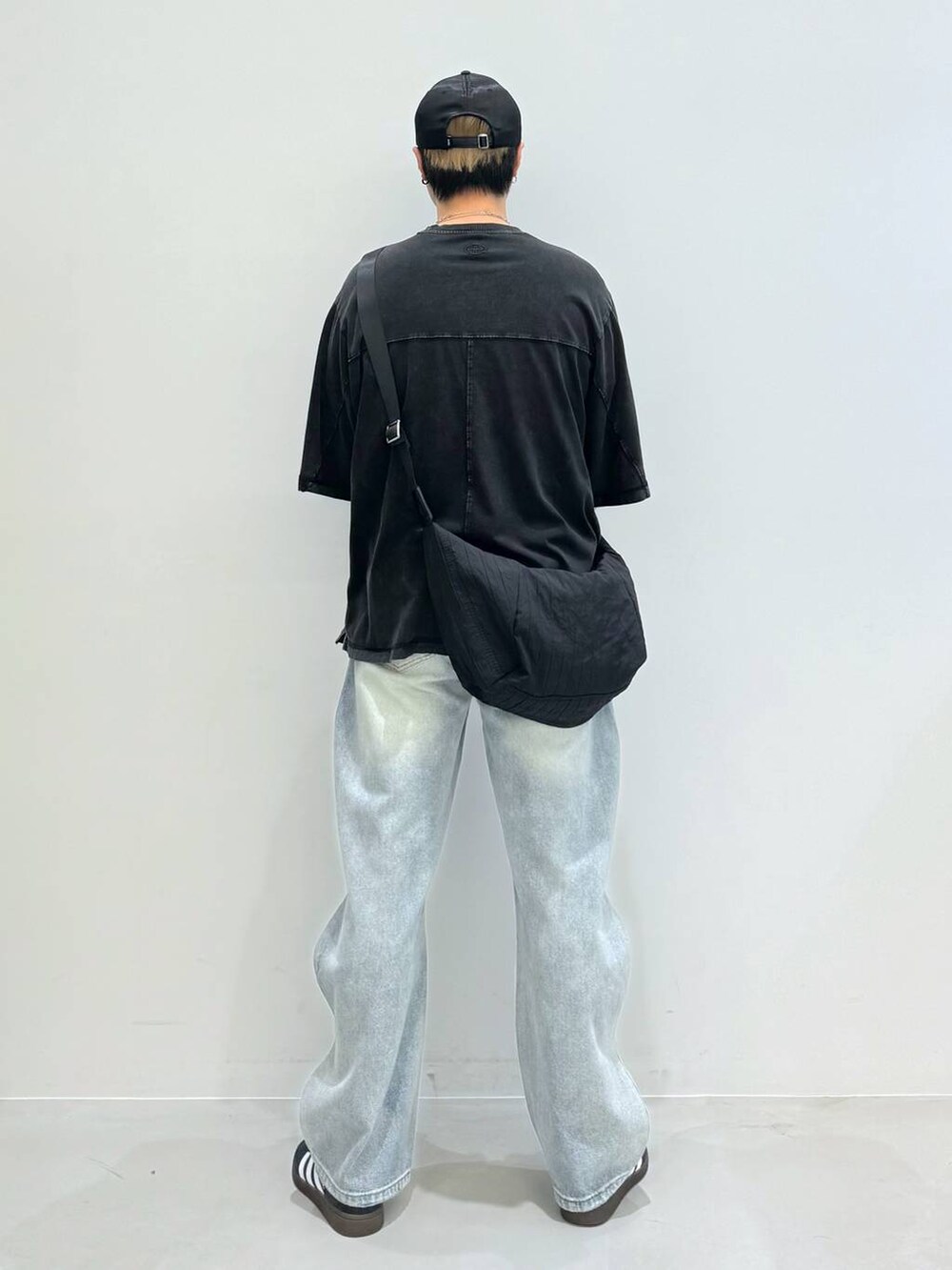 ブルー系のデニムパンツ、ブラック系のショルダーバッグ、ブラック系のスニーカーを着用したメンズの夏コーディネートの3枚目の写真