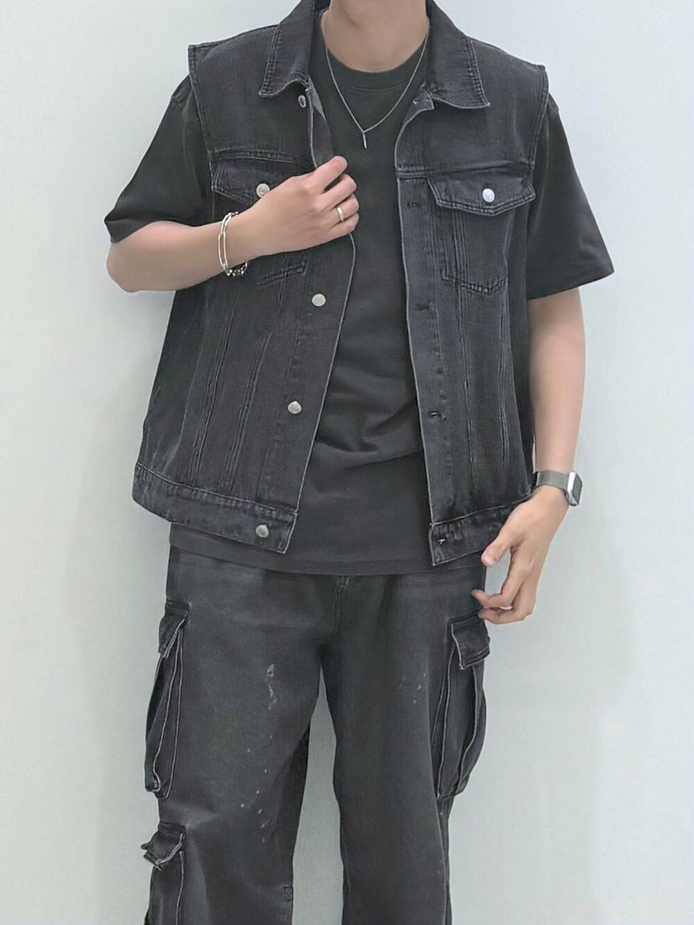 ブラック系のデニムパンツ、ブラック系のベスト、グレー系のTシャツ/カットソーを着用したメンズの春コーディネートの2枚目の写真