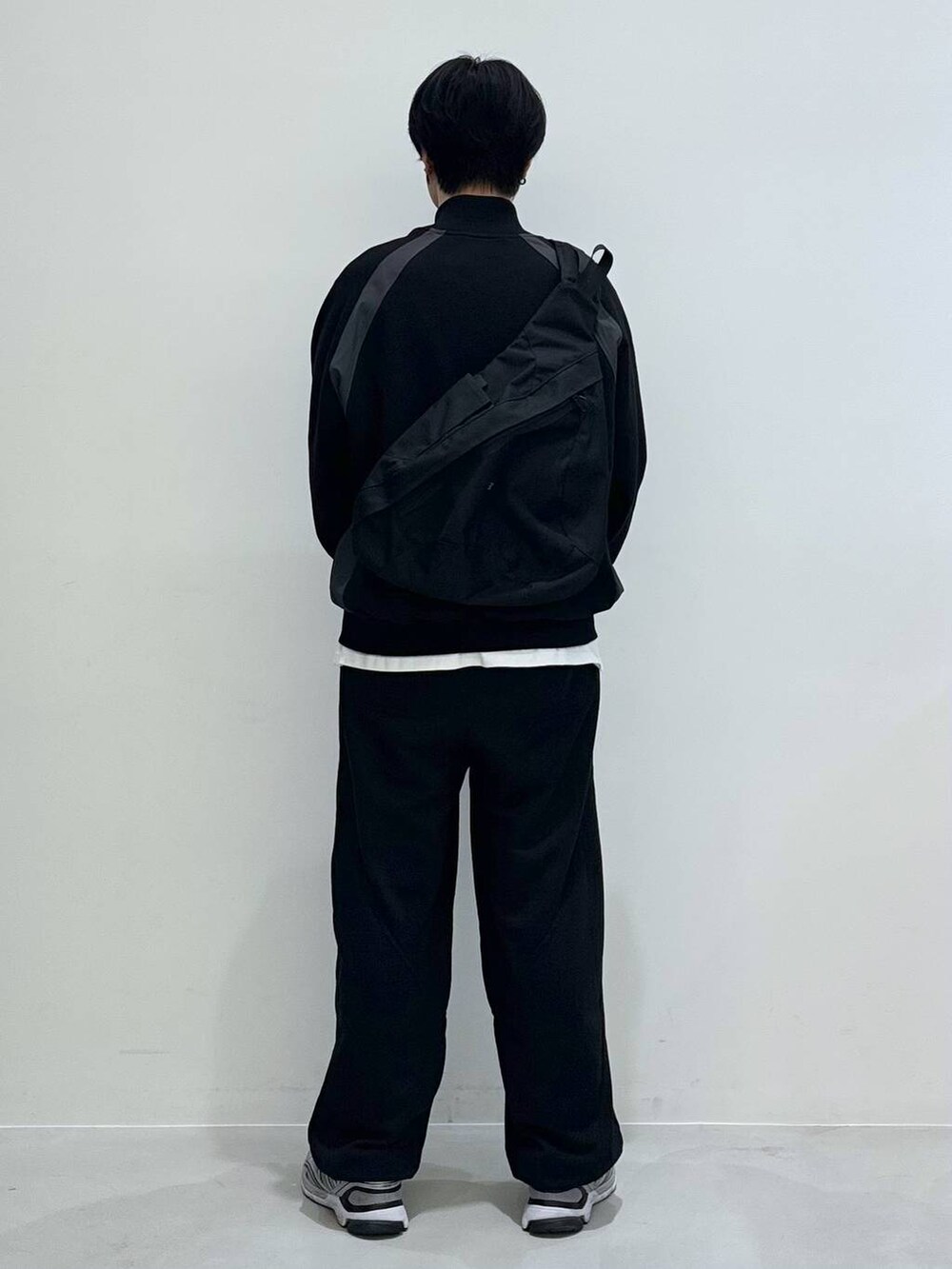 ブラック系のバックパック/リュック、ブラック系のスウェットパンツ、ホワイト系のTシャツ/カットソーを着用したメンズの冬コーディネートの3枚目の写真