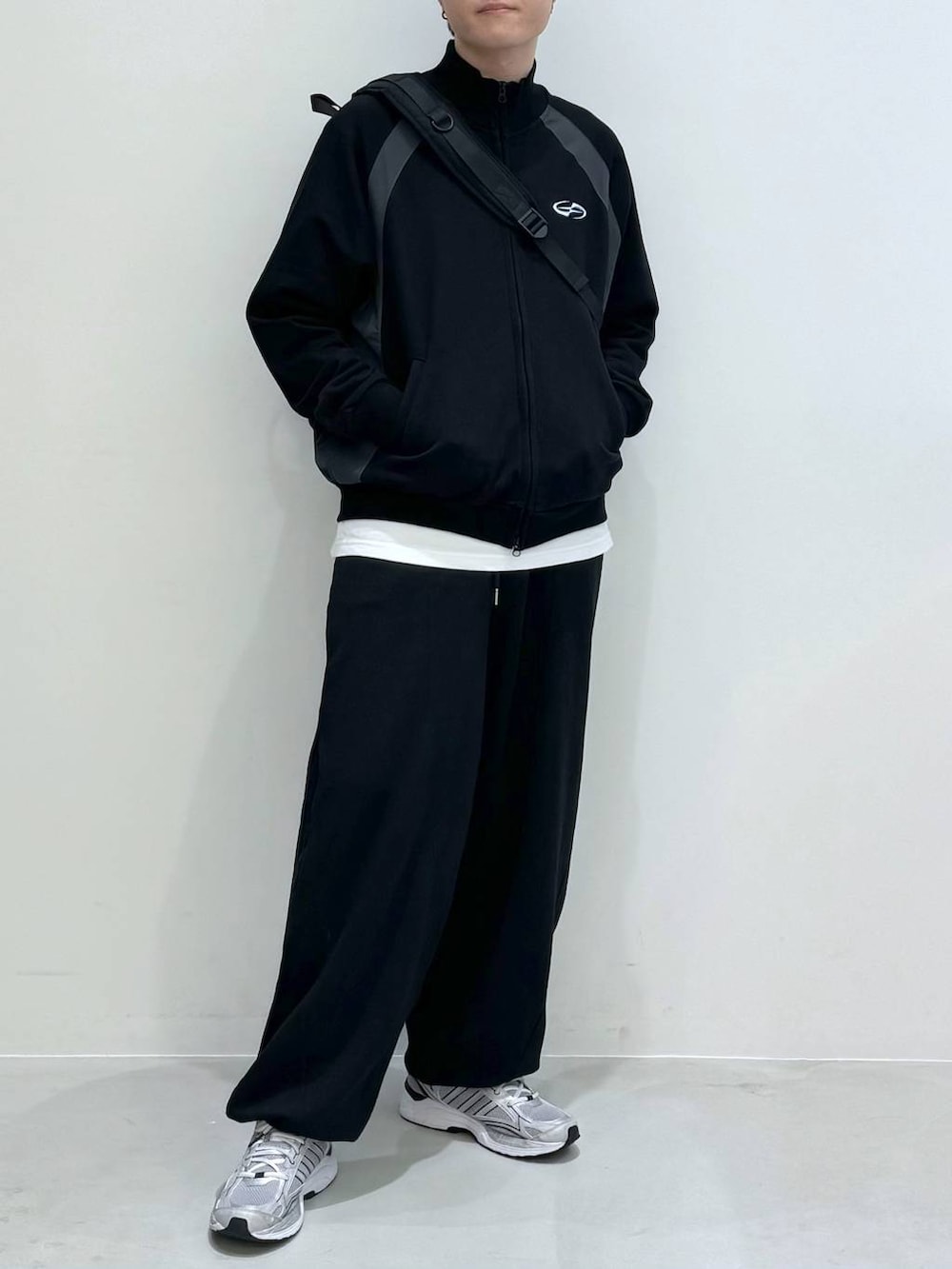 ブラック系のバックパック/リュック、ブラック系のスウェットパンツ、ホワイト系のTシャツ/カットソーを着用したメンズの冬コーディネートの2枚目の写真