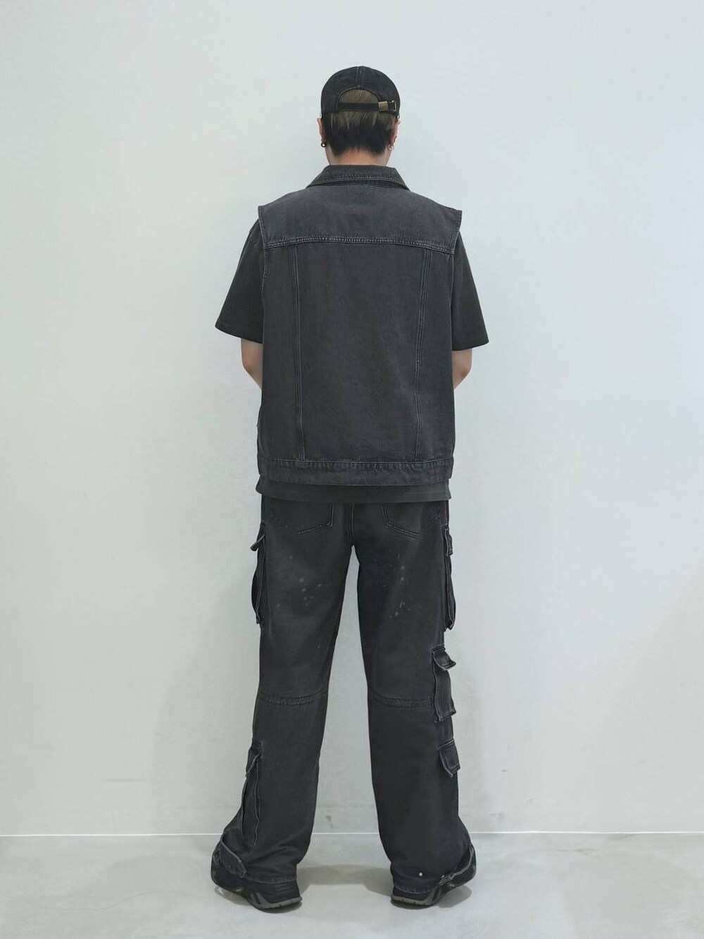 ブラック系のデニムパンツ、ブラック系のベスト、グレー系のTシャツ/カットソーを着用したメンズの春コーディネートの4枚目の写真