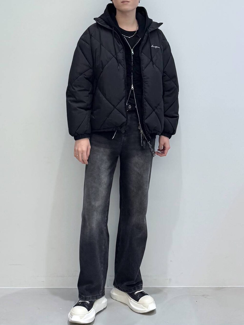 ブラック系のダウンジャケット/コート、ブラック系のデニムパンツ、ブラック系のパーカーを着用したメンズの冬コーディネートの3枚目の写真