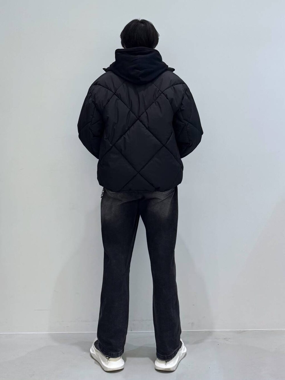 ブラック系のダウンジャケット/コート、ブラック系のデニムパンツ、ブラック系のパーカーを着用したメンズの冬コーディネートの4枚目の写真