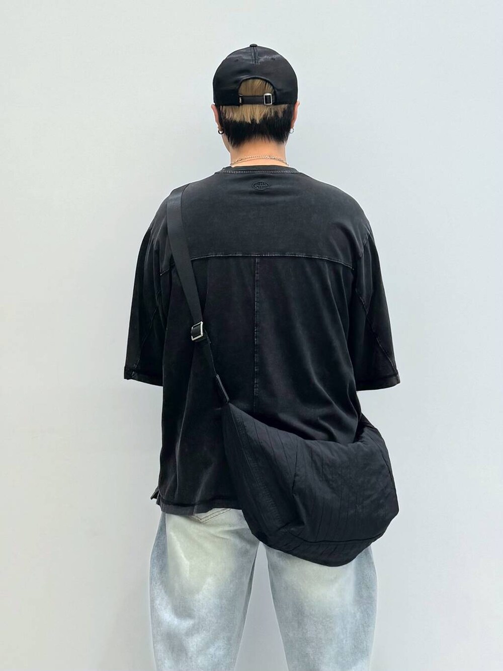 ブルー系のデニムパンツ、ブラック系のショルダーバッグ、ブラック系のスニーカーを着用したメンズの夏コーディネートの4枚目の写真