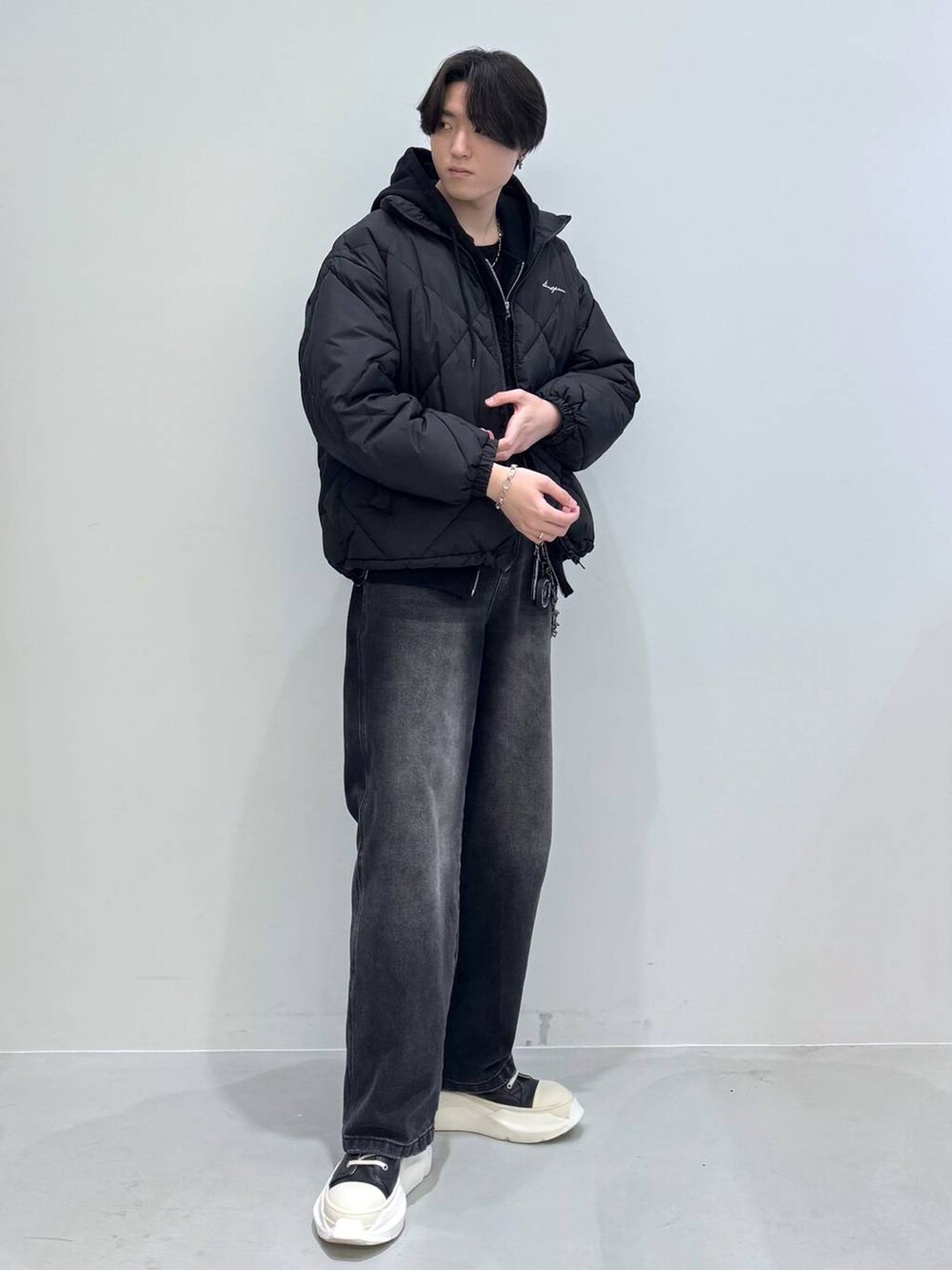 ブラック系のダウンジャケット/コート、ブラック系のデニムパンツ、ブラック系のパーカーを着用したメンズの冬コーディネートの6枚目の写真