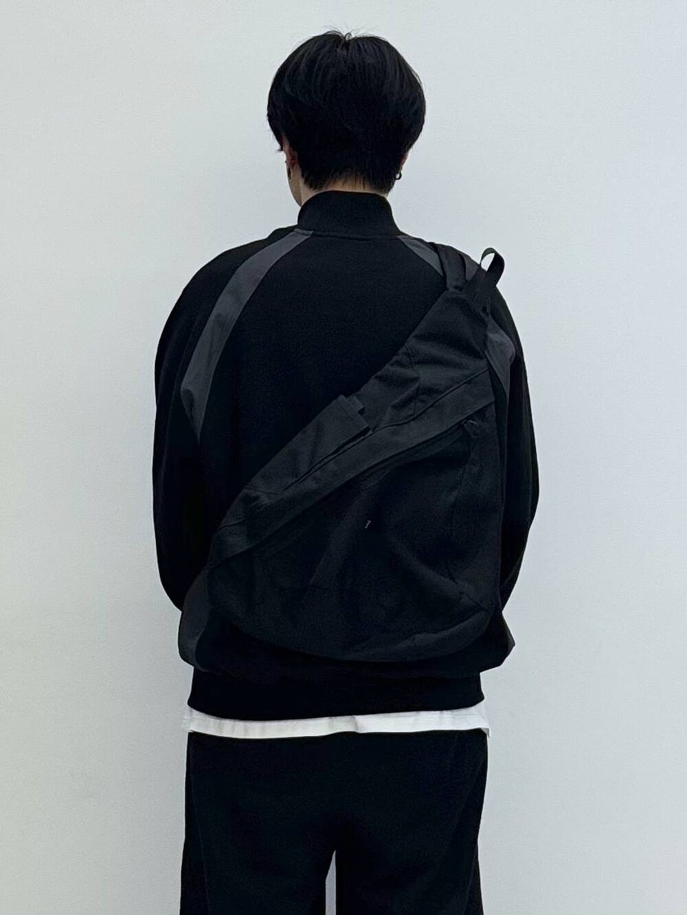 ブラック系のバックパック/リュック、ブラック系のスウェットパンツ、ホワイト系のTシャツ/カットソーを着用したメンズの冬コーディネートの4枚目の写真