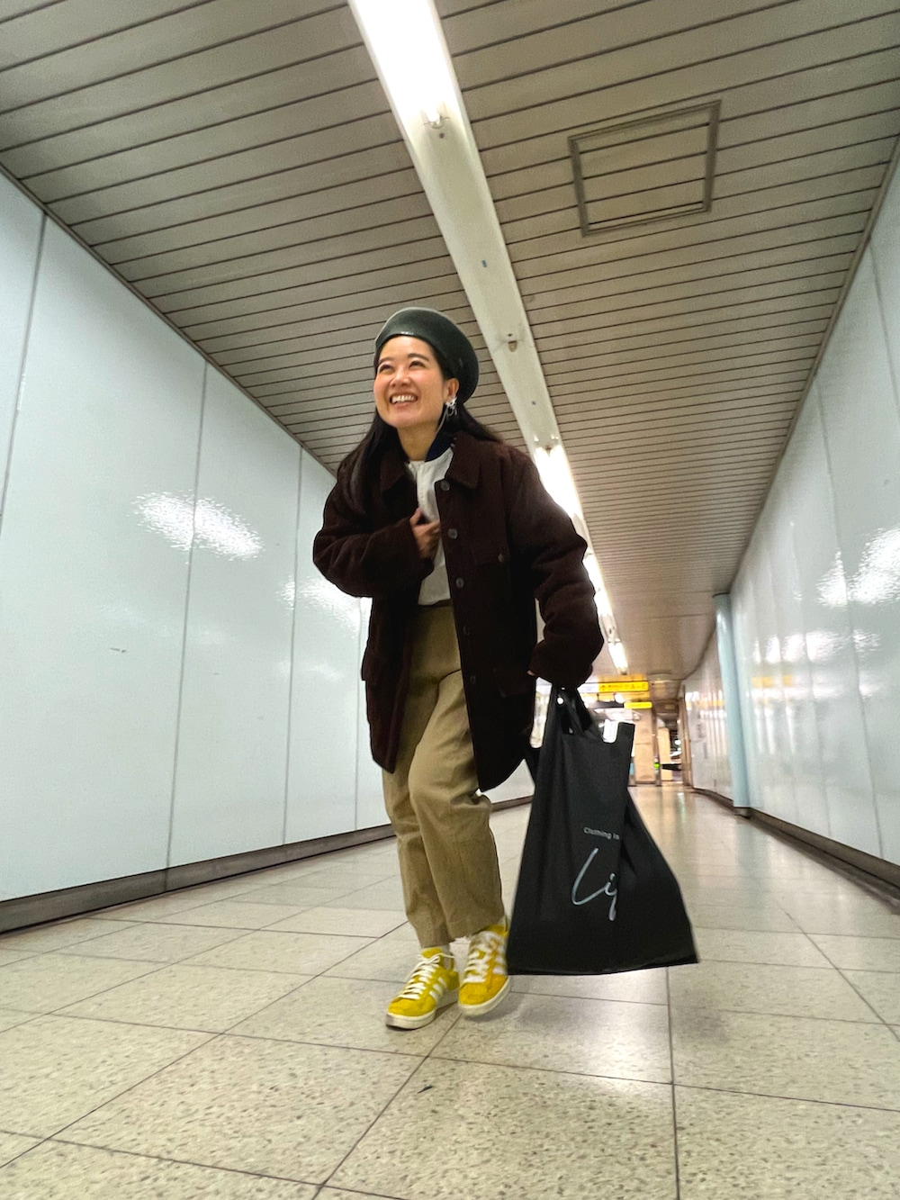 ホワイト系のジャージ、ベージュ系のチノパンツ、イエロー系のスニーカーを着用したレディースの春コーディネートの3枚目の写真