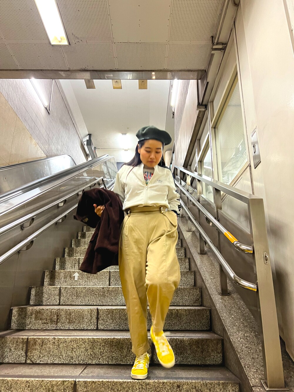 ホワイト系のジャージ、ベージュ系のチノパンツ、イエロー系のスニーカーを着用したレディースの春コーディネートの2枚目の写真