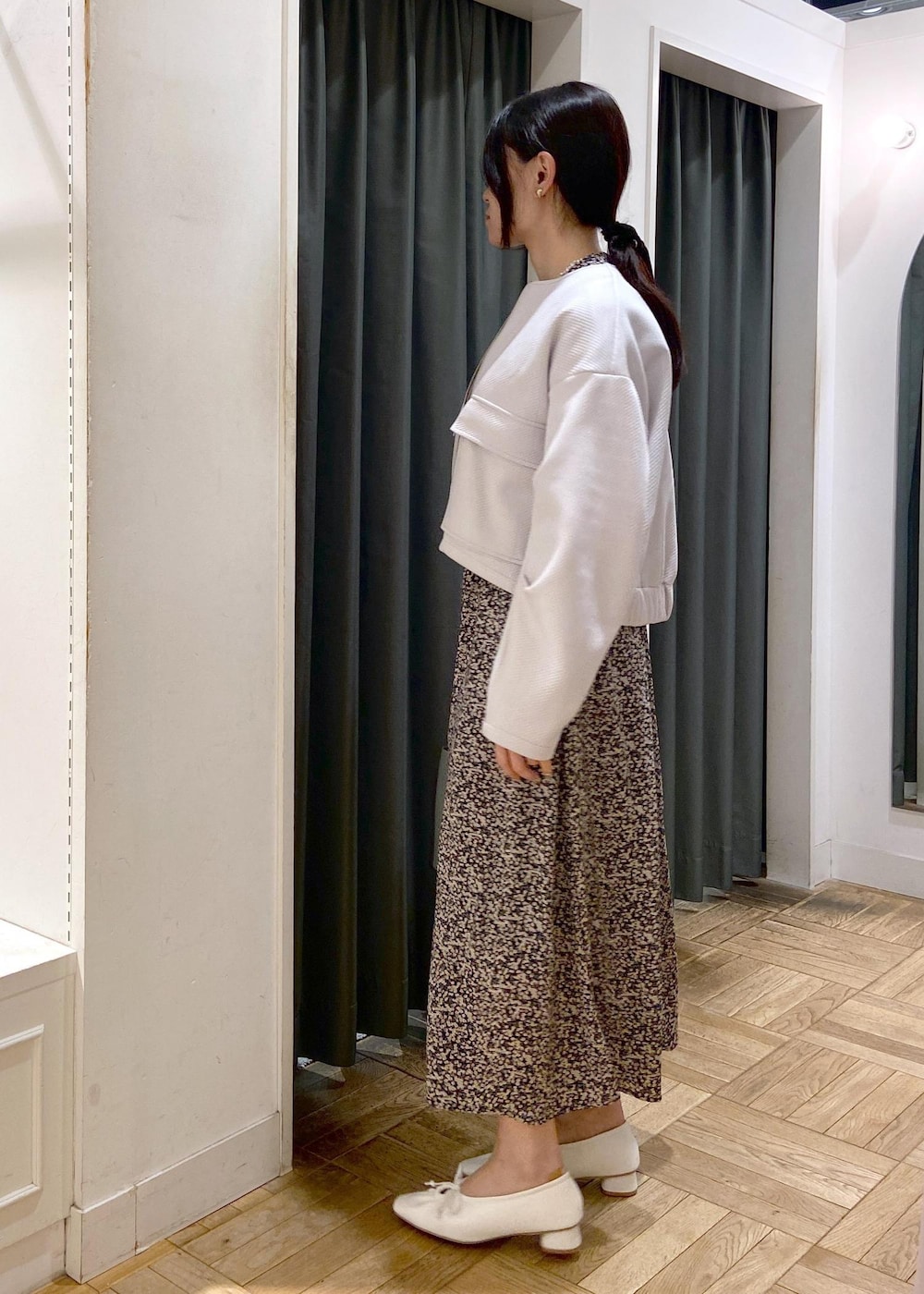 ブルー系のハンドバッグ、ホワイト系のパンプス、グレー系のブルゾンを着用したレディースの春コーディネートの4枚目の写真