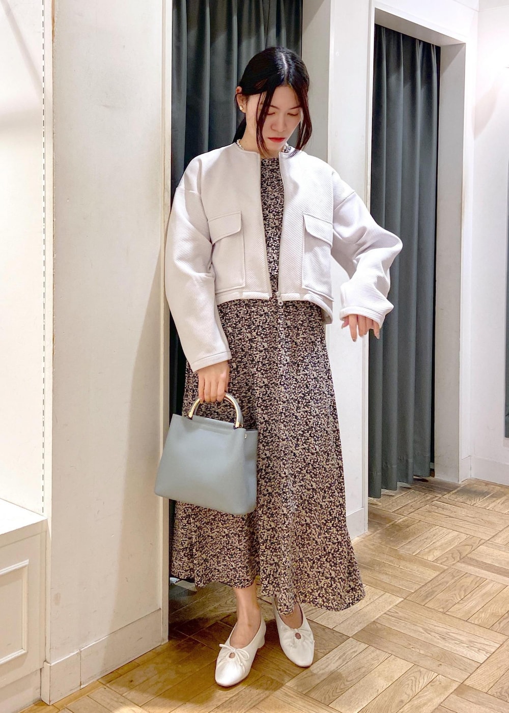 ブルー系のハンドバッグ、ホワイト系のパンプス、グレー系のブルゾンを着用したレディースの春コーディネートの3枚目の写真
