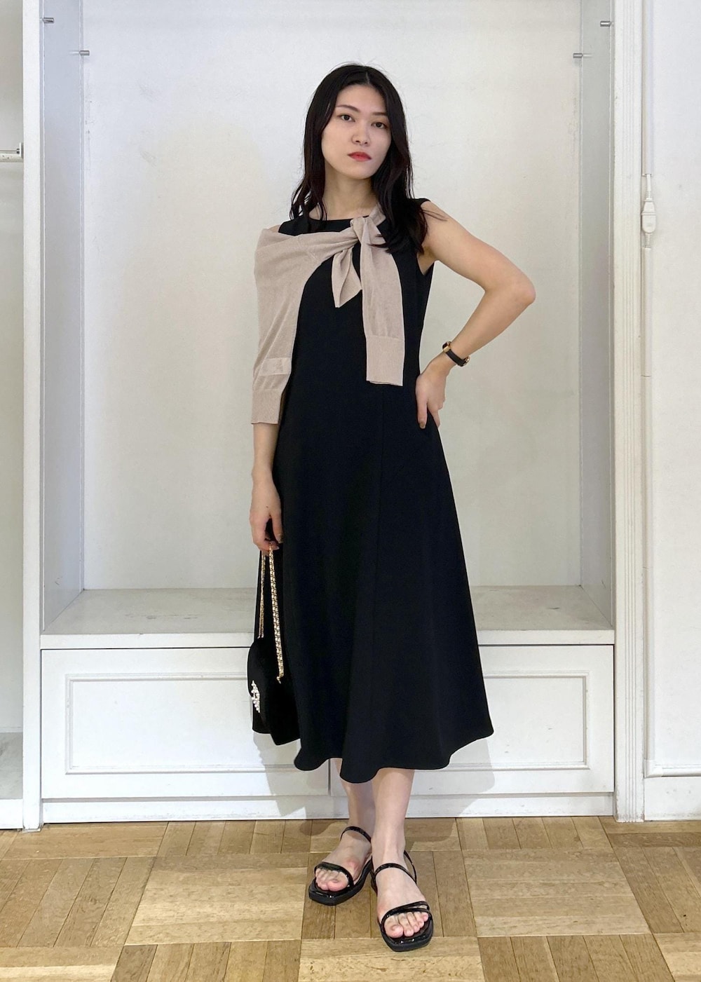 ブラック系のドレス、ブラック系のショルダーバッグ、ベージュ系のカーディガン/ボレロを着用したレディースの夏コーディネートの2枚目の写真