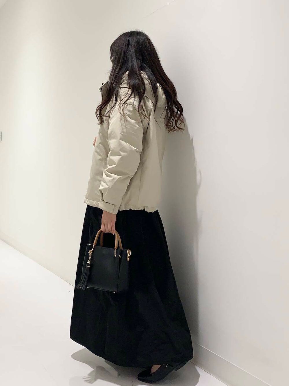 ブラック系のトートバッグ、ベージュ系のダウンジャケット/コート、ブルー系のニット/セーターを着用したレディースの冬コーディネートの2枚目の写真