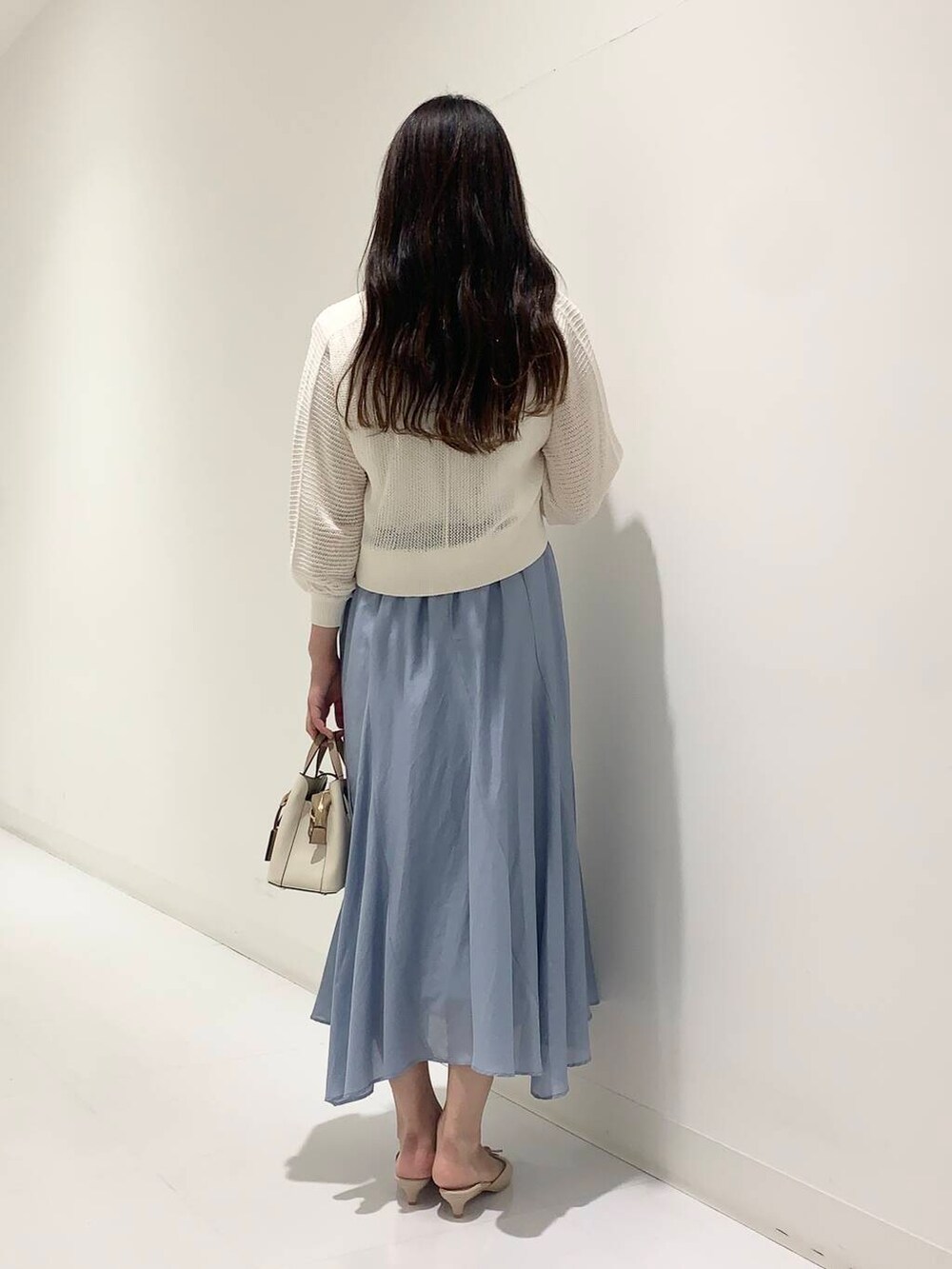 ホワイト系のハンドバッグ、ホワイト系のカーディガン/ボレロ、ベージュ系のサンダルを着用したレディースの夏コーディネートの3枚目の写真