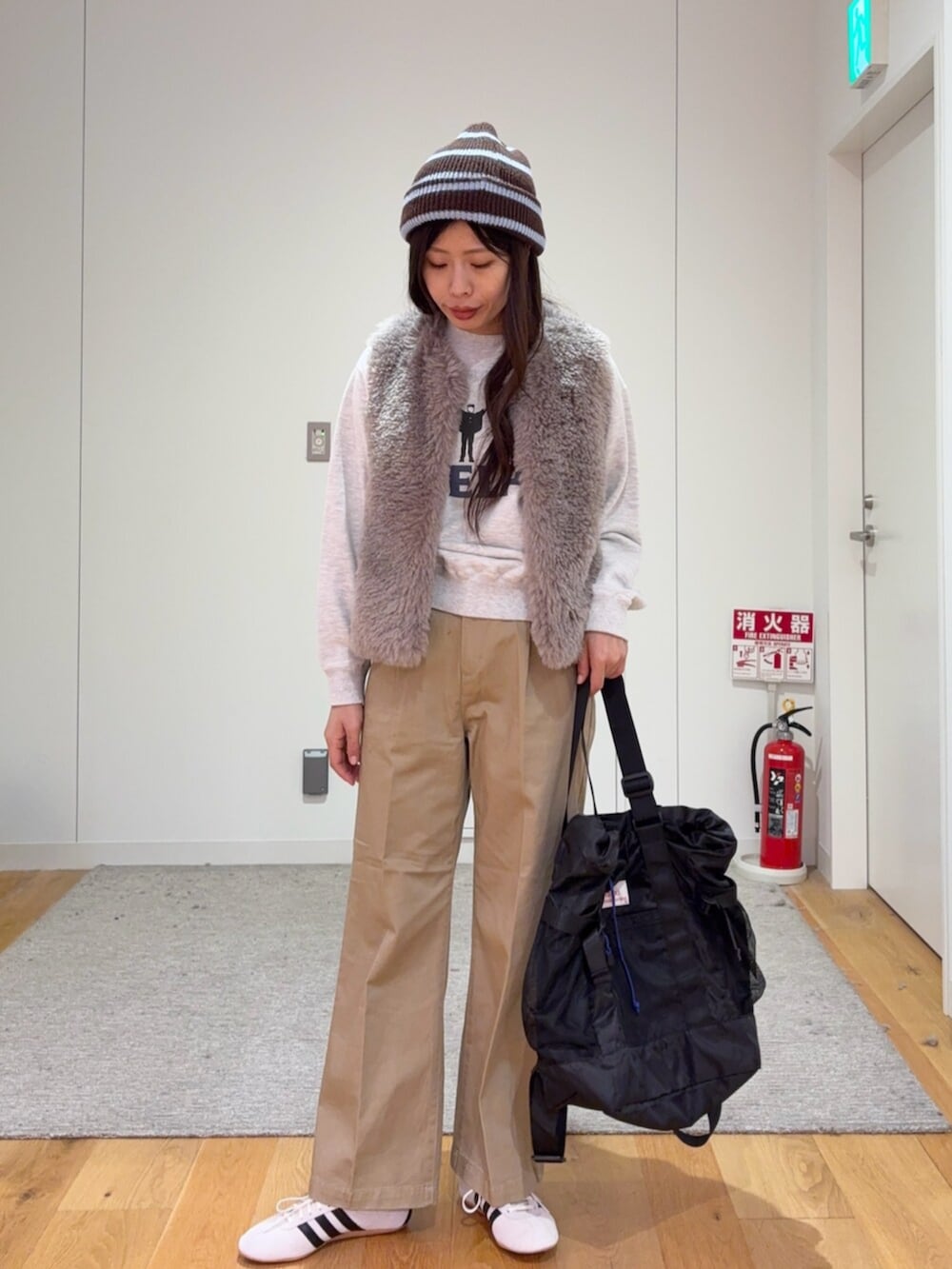 グレー系のダウンベスト、ベージュ系のその他パンツ、ブラック系のトートバッグを着用したレディースの秋コーディネートの2枚目の写真