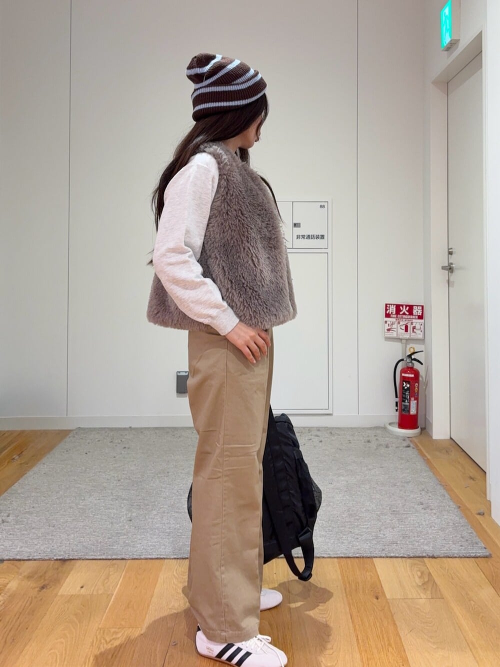 グレー系のダウンベスト、ベージュ系のその他パンツ、ブラック系のトートバッグを着用したレディースの秋コーディネートの3枚目の写真