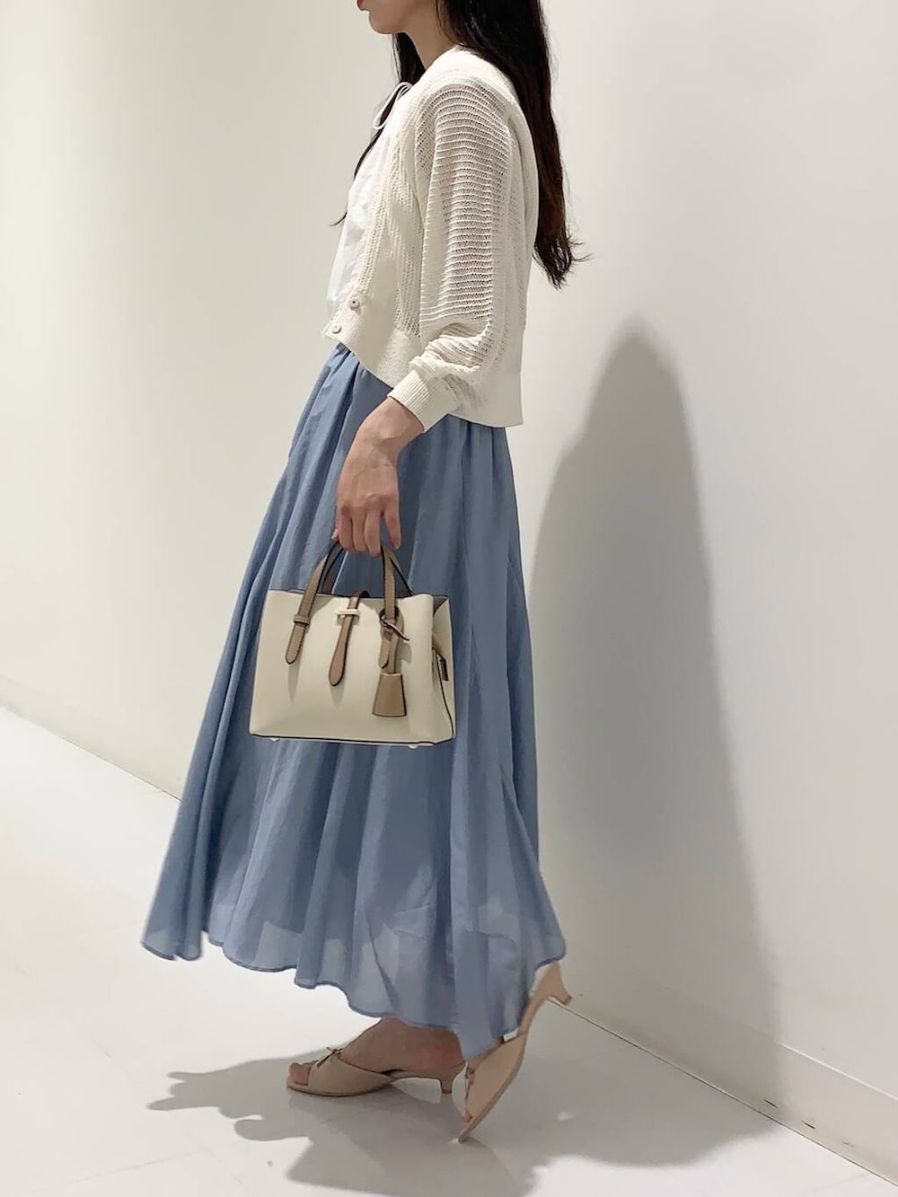 ホワイト系のハンドバッグ、ホワイト系のカーディガン/ボレロ、ベージュ系のサンダルを着用したレディースの夏コーディネートの2枚目の写真