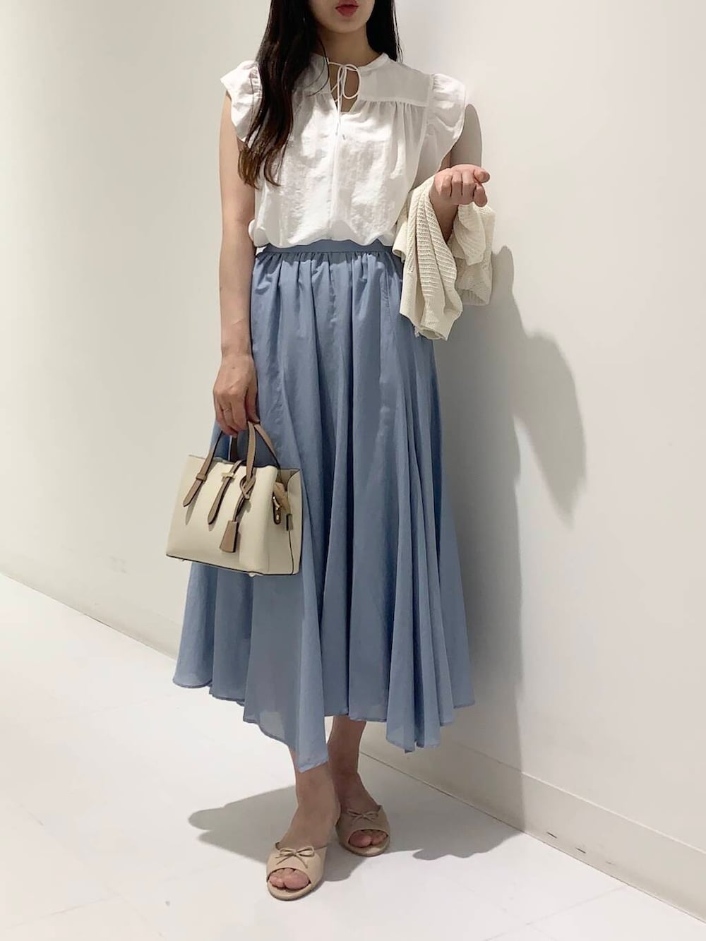 ホワイト系のハンドバッグ、ホワイト系のカーディガン/ボレロ、ベージュ系のサンダルを着用したレディースの夏コーディネートの4枚目の写真