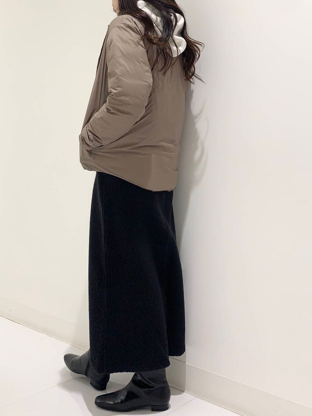 ブラウン系のダウンジャケット/コート、ブラック系のブーツ、ホワイト系のパーカーを着用したレディースの秋コーディネートの2枚目の写真