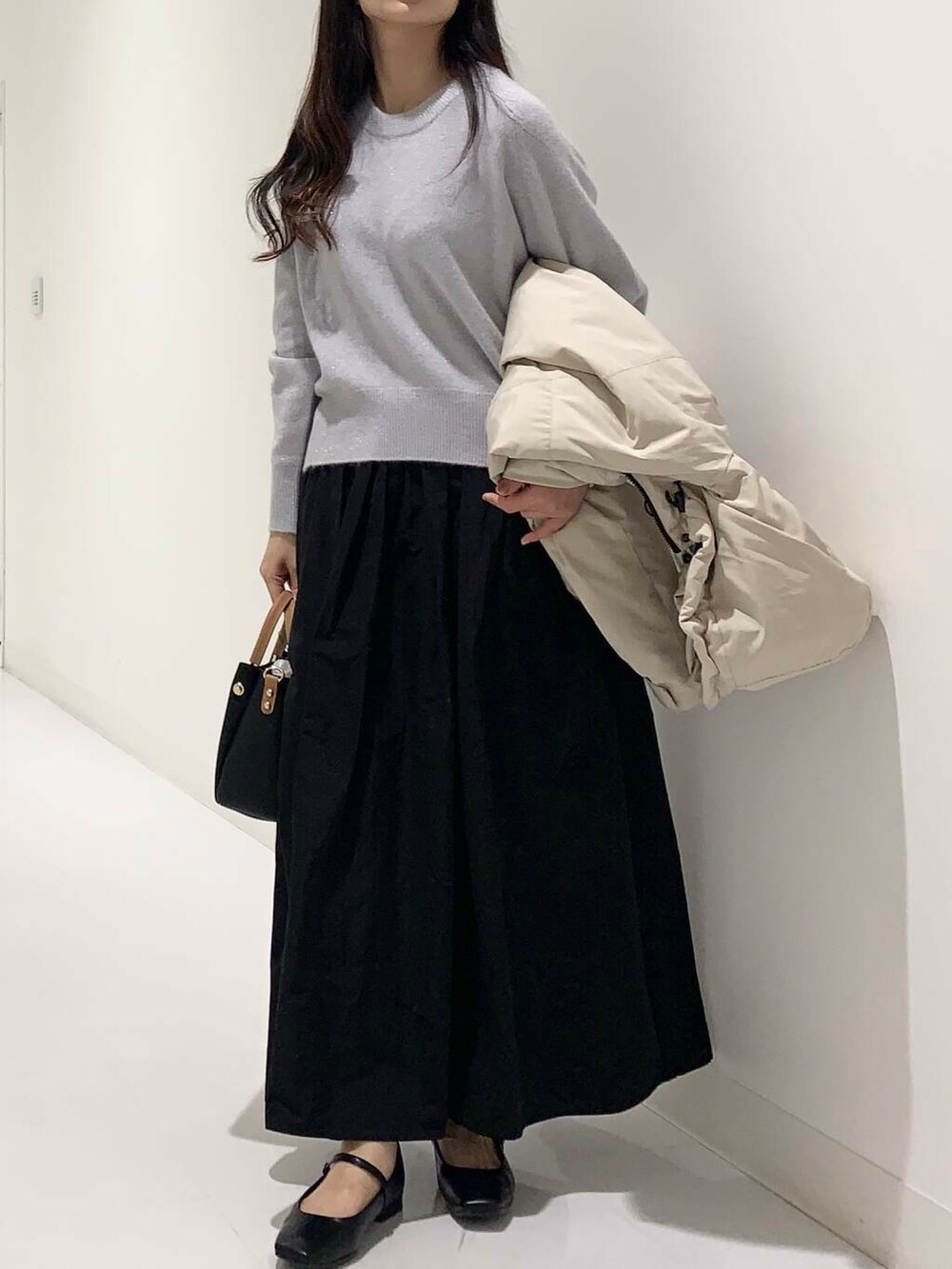 ブラック系のトートバッグ、ベージュ系のダウンジャケット/コート、ブルー系のニット/セーターを着用したレディースの冬コーディネートの4枚目の写真