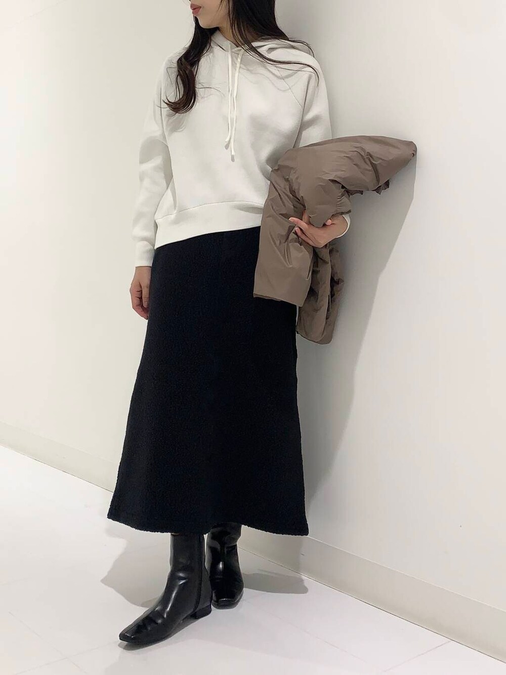 ブラウン系のダウンジャケット/コート、ブラック系のブーツ、ホワイト系のパーカーを着用したレディースの秋コーディネートの3枚目の写真