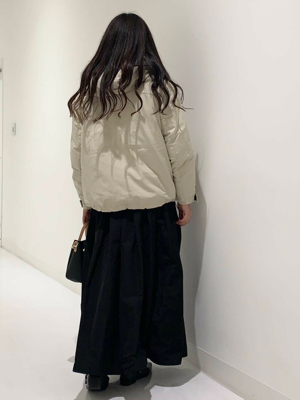 ブラック系のトートバッグ、ベージュ系のダウンジャケット/コート、ブルー系のニット/セーターを着用したレディースの冬コーディネートの3枚目の写真