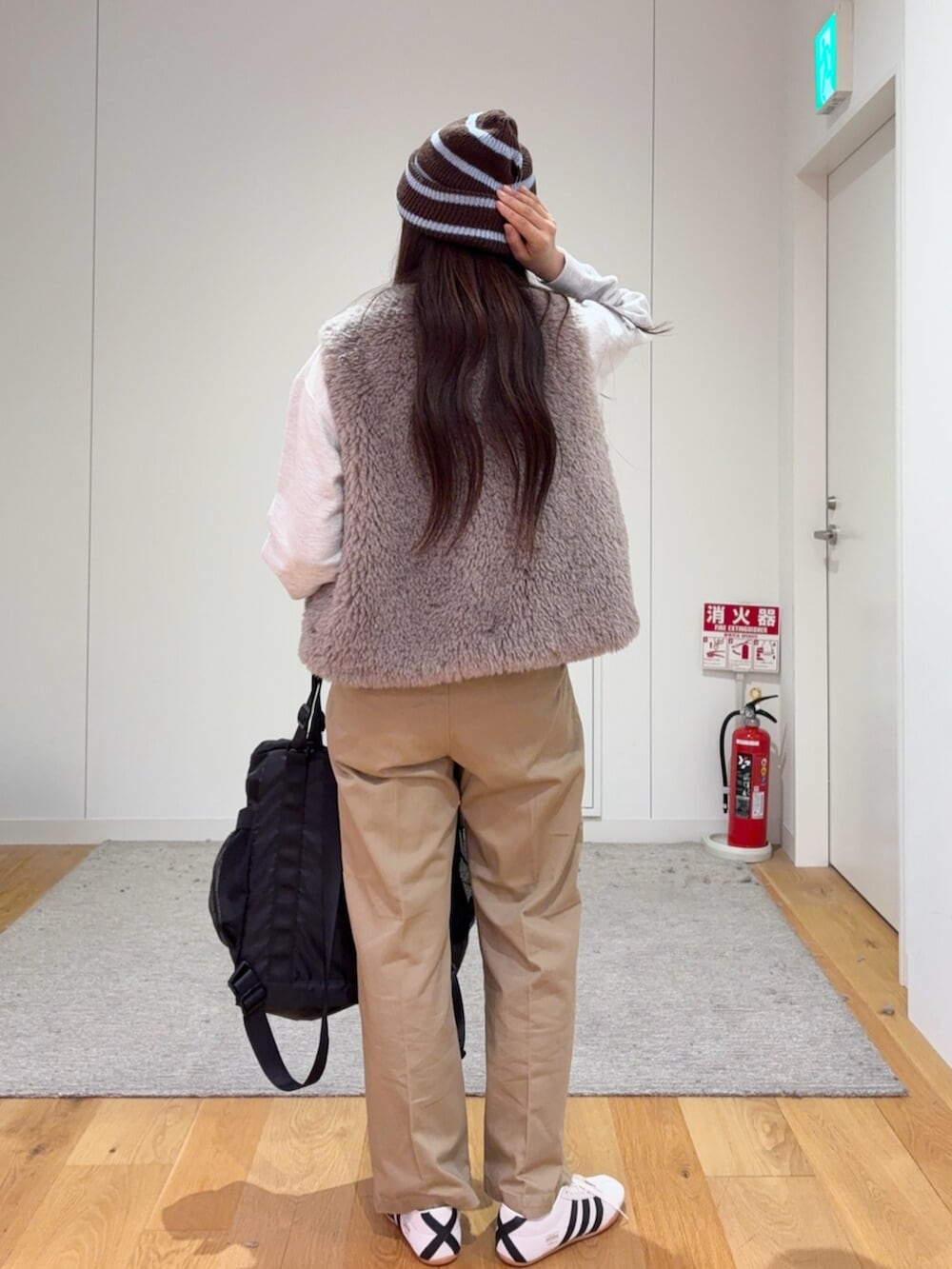グレー系のダウンベスト、ベージュ系のその他パンツ、ブラック系のトートバッグを着用したレディースの秋コーディネートの4枚目の写真