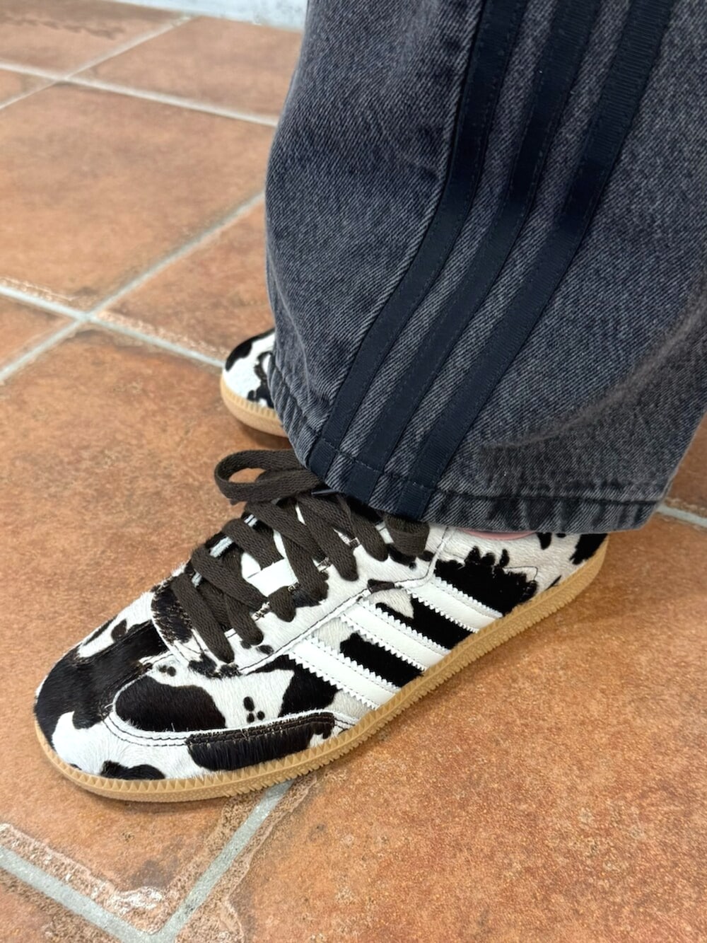 ホワイト系のジャージ、ブラック系のデニムパンツ、ブラウン系のスニーカーを着用したレディースの秋コーディネートの2枚目の写真