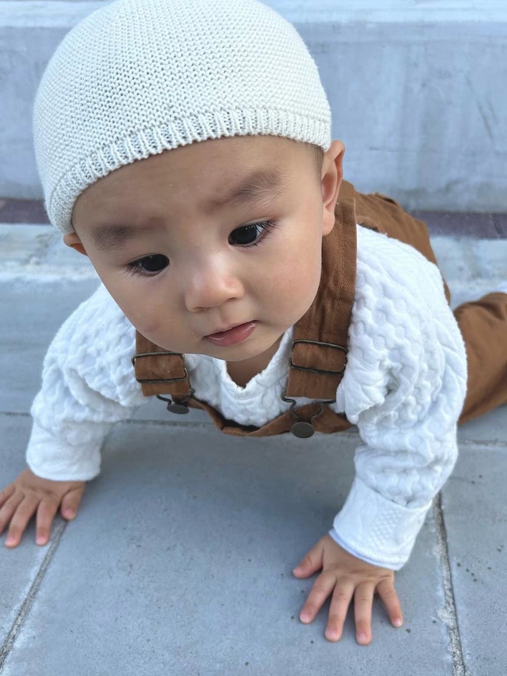 ブラウン系のオールインワン・サロペット、ホワイト系のトップス、ホワイト系のベビーシューズ/ベビーソックスを着用したキッズの春コーディネートの2枚目の写真