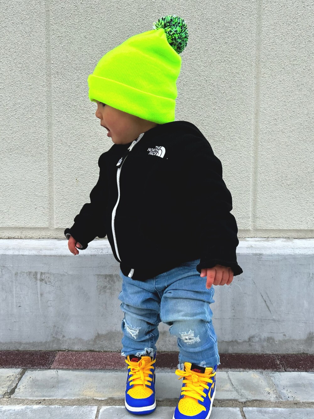 ブラック系のパーカー、ブルー系のデニムパンツ、ブルー系のスニーカーを着用したキッズの春コーディネートの2枚目の写真