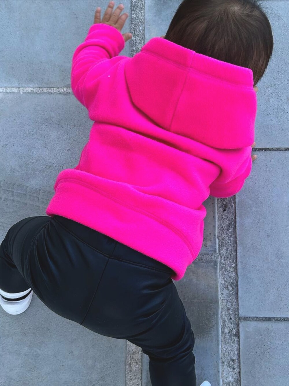 ピンク系のトップス、ブラック系のパンツ、ホワイト系のスニーカーを着用したキッズの春コーディネートの2枚目の写真