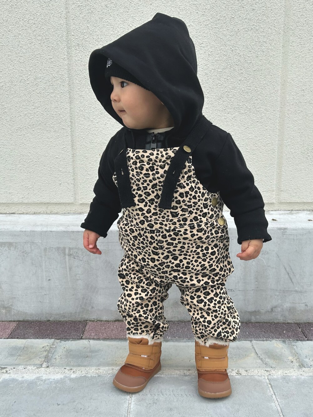ブラウン系のオールインワン・サロペット、ブラック系のニットキャップ/ビーニー、ブラウン系のベビーシューズ/ベビーソックスを着用したキッズの春コーディネートの2枚目の写真