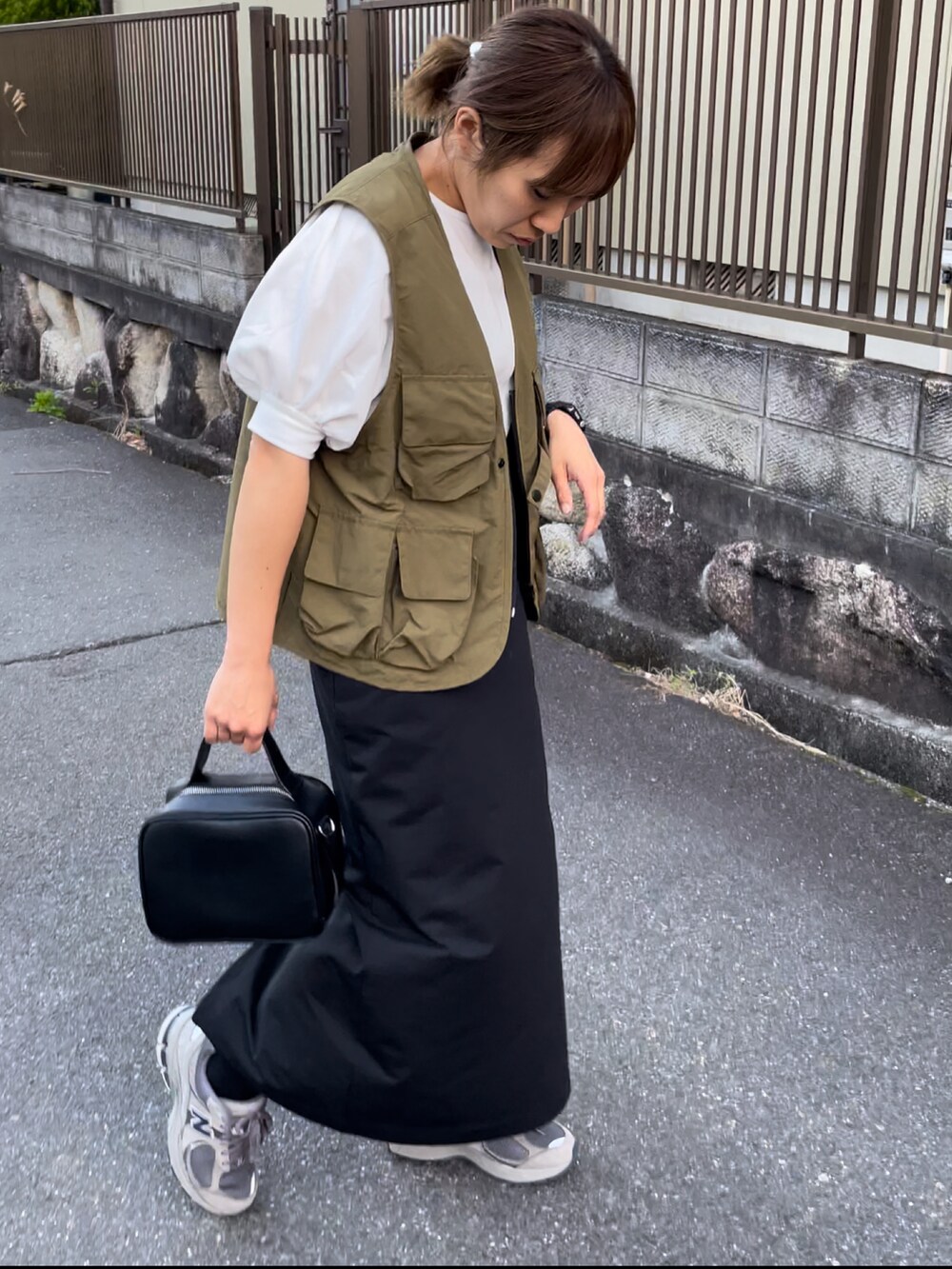 ブラック系のハンドバッグ、ホワイト系のTシャツ/カットソー、グリーン系のその他アウターを着用したレディースの春コーディネートの2枚目の写真