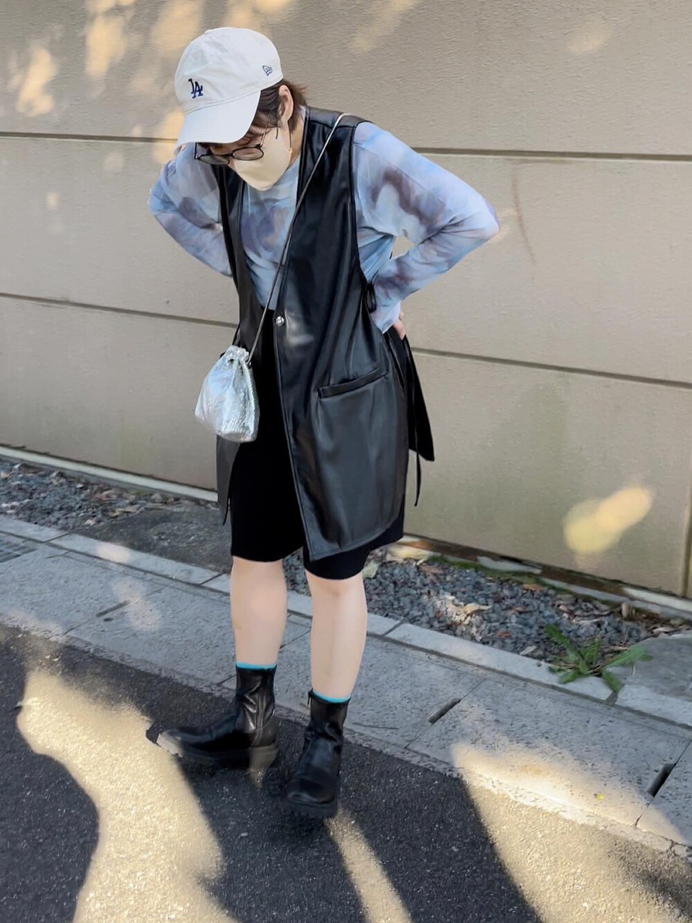 ブラック系のベスト、ブルー系のTシャツ/カットソー、ベージュ系のキャップを着用したレディースの秋コーディネートの3枚目の写真