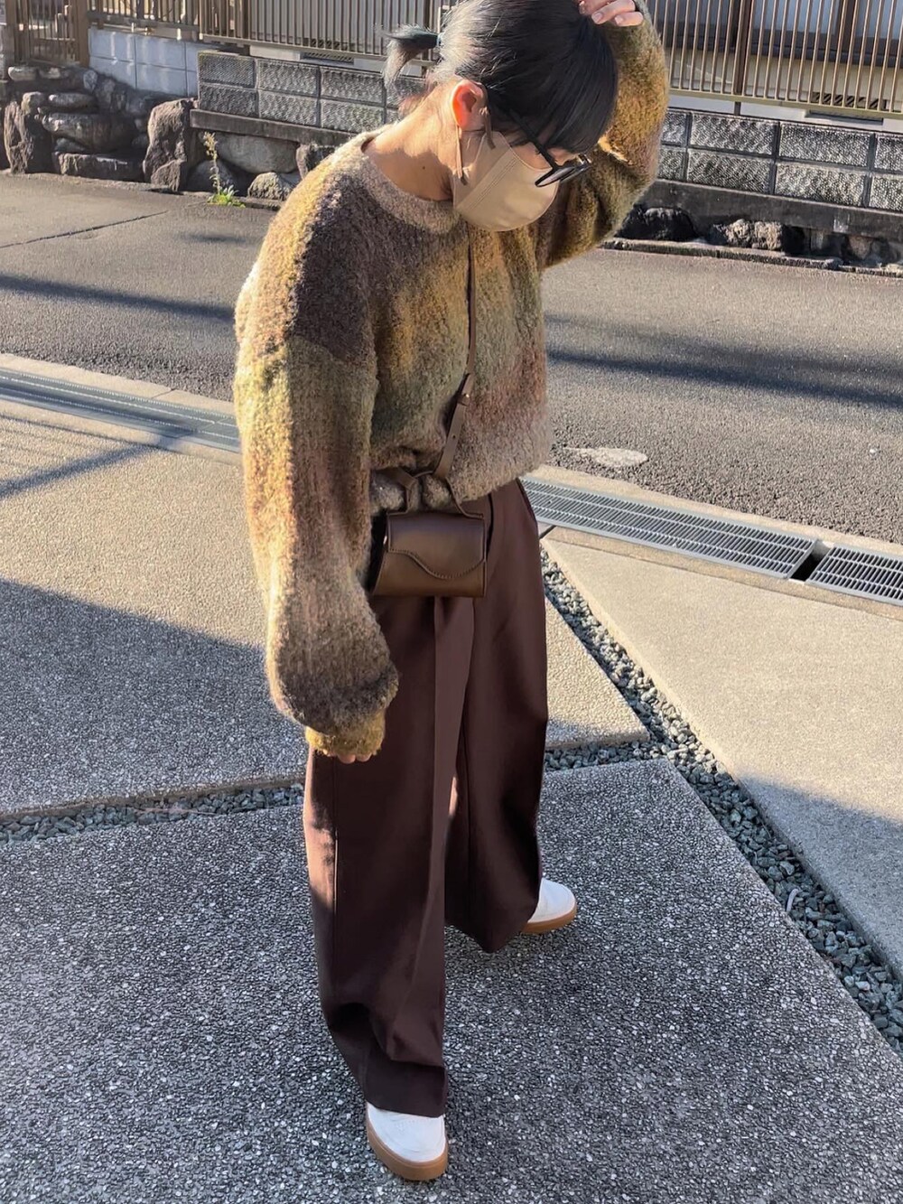 イエロー系のニット/セーター、ブラウン系のスラックスを着用したレディースの秋コーディネートの3枚目の写真