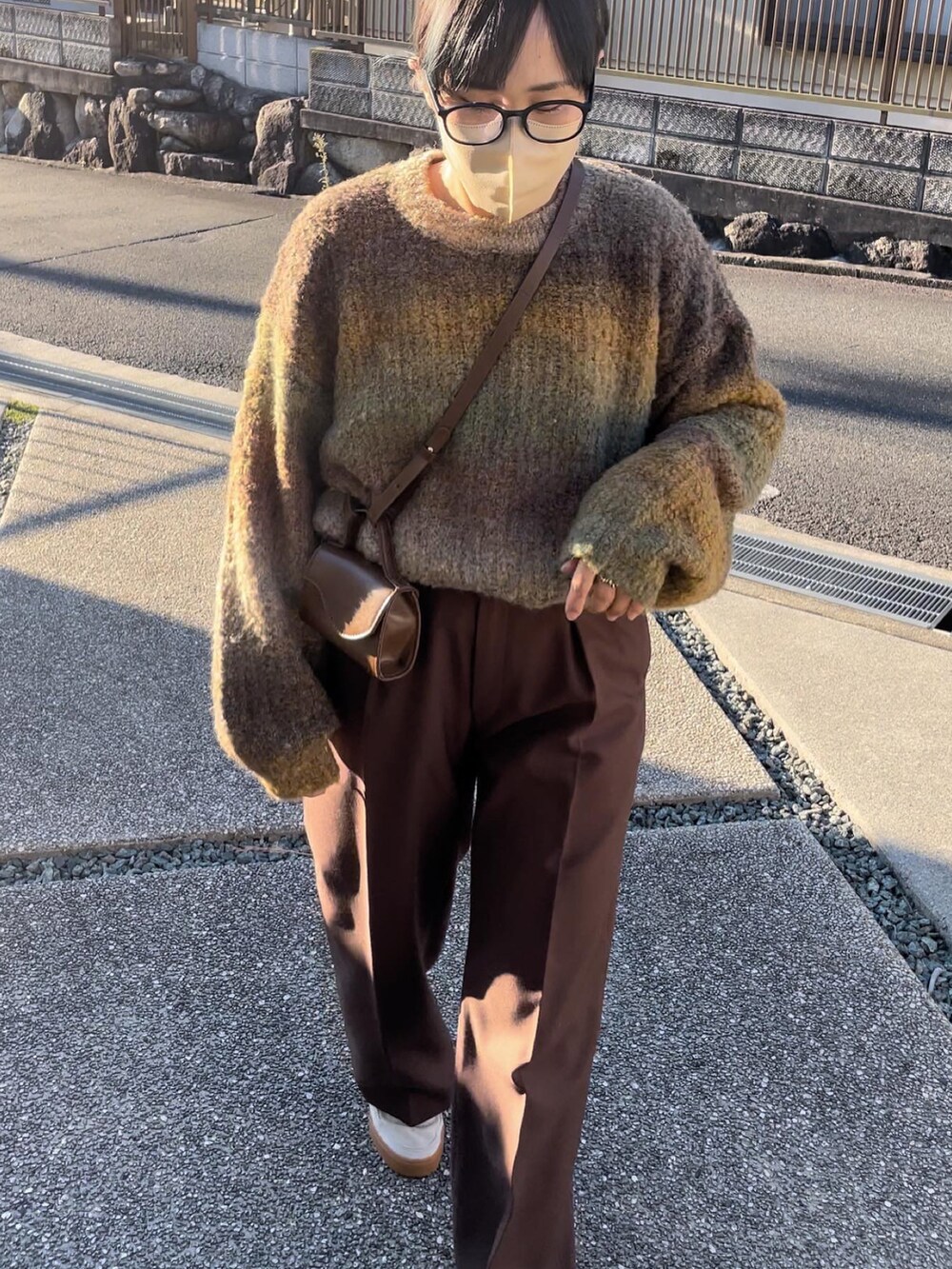 イエロー系のニット/セーター、ブラウン系のスラックスを着用したレディースの秋コーディネートの2枚目の写真