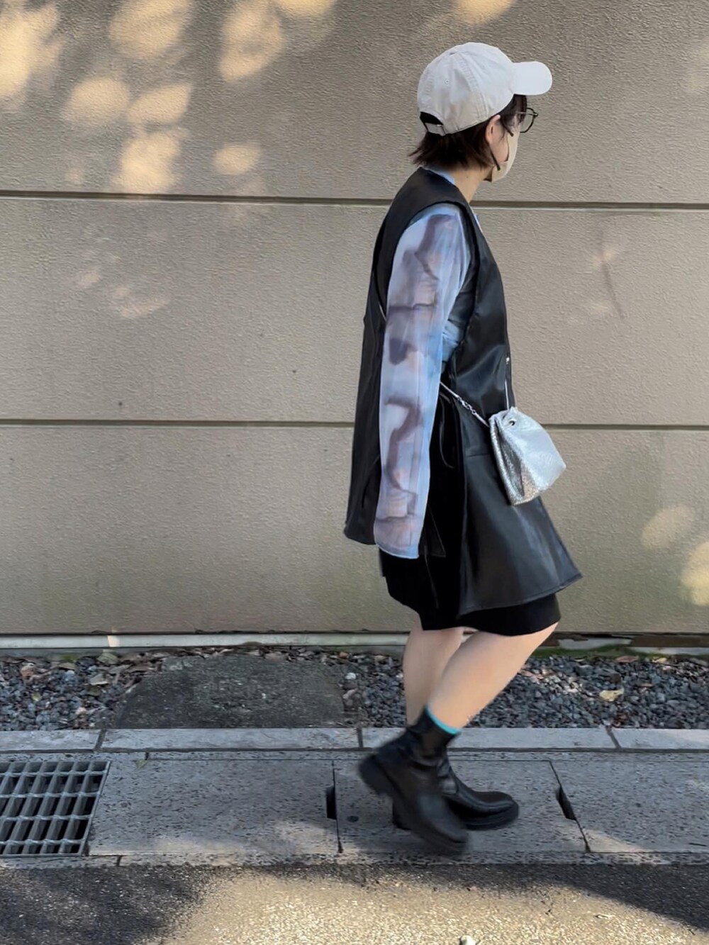 ブラック系のベスト、ブルー系のTシャツ/カットソー、ベージュ系のキャップを着用したレディースの秋コーディネートの2枚目の写真