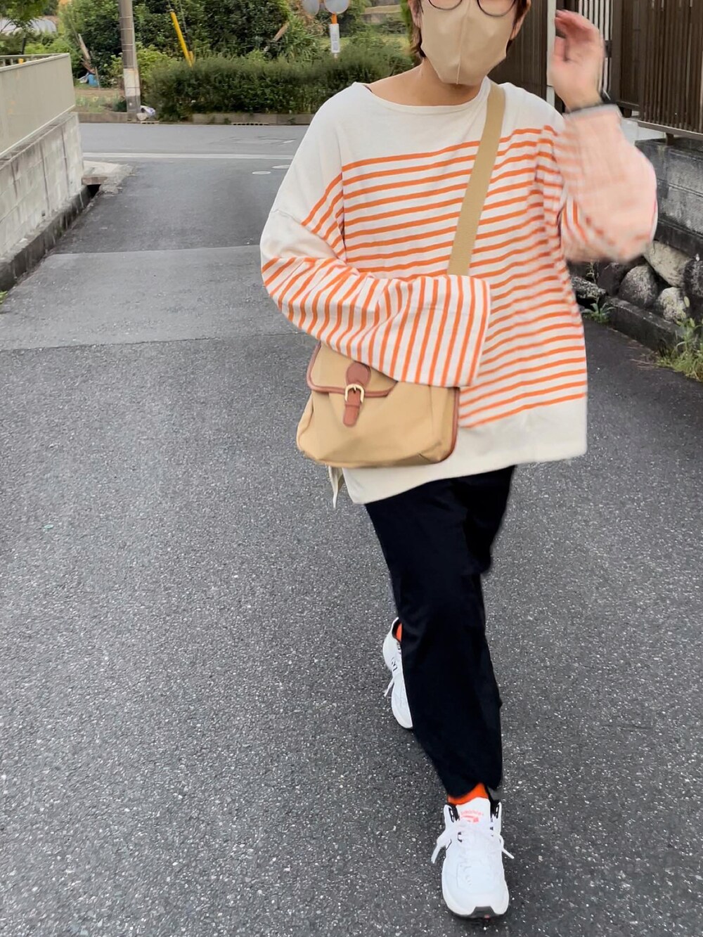 ブラック系のスカート、ホワイト系のスニーカー、オレンジ系のTシャツ/カットソーを着用したレディースの秋コーディネートの3枚目の写真