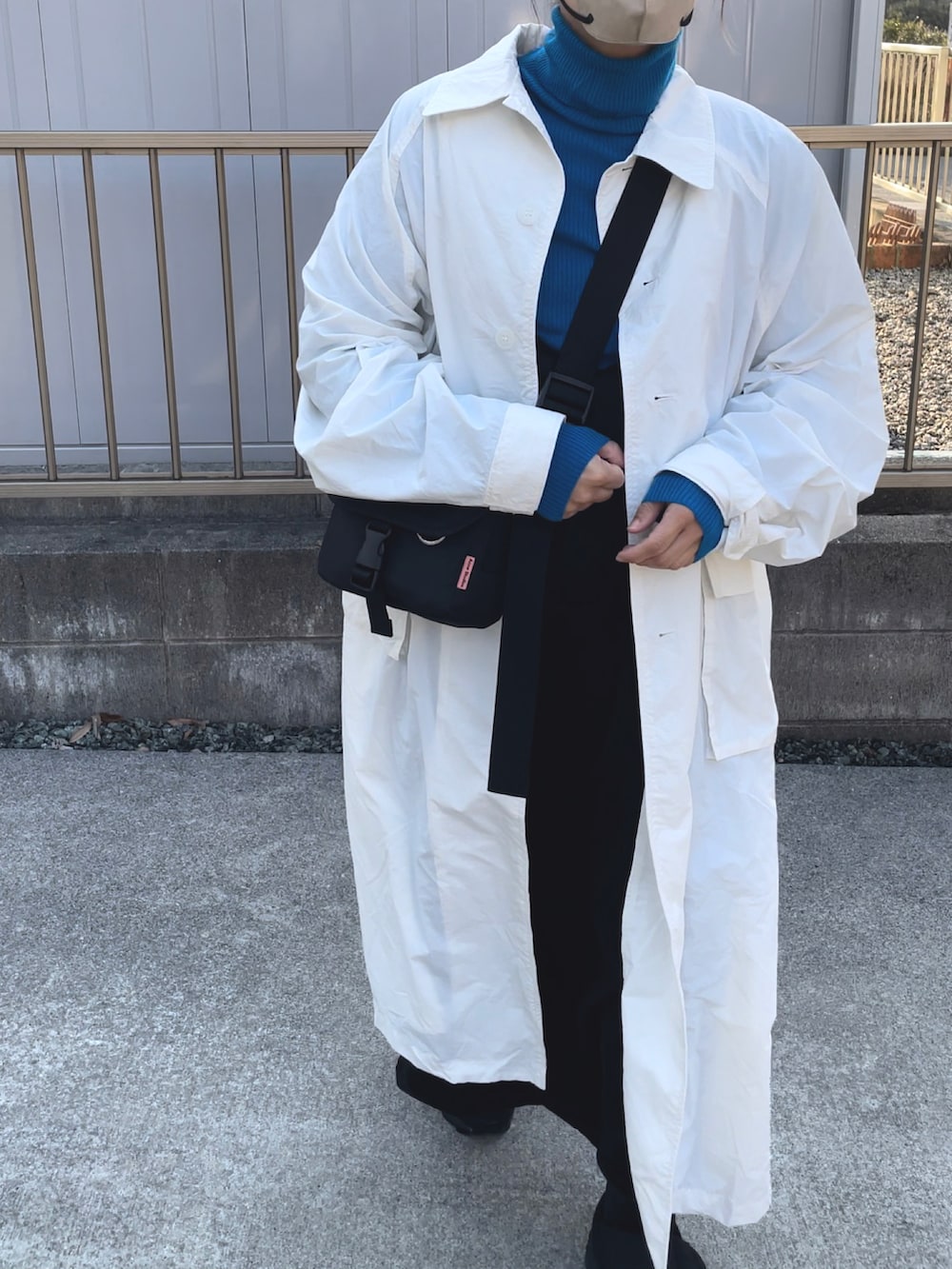 ホワイト系のステンカラーコート、ブルー系のニット/セーター、ブラック系のバッグを着用したレディースの春コーディネートの3枚目の写真