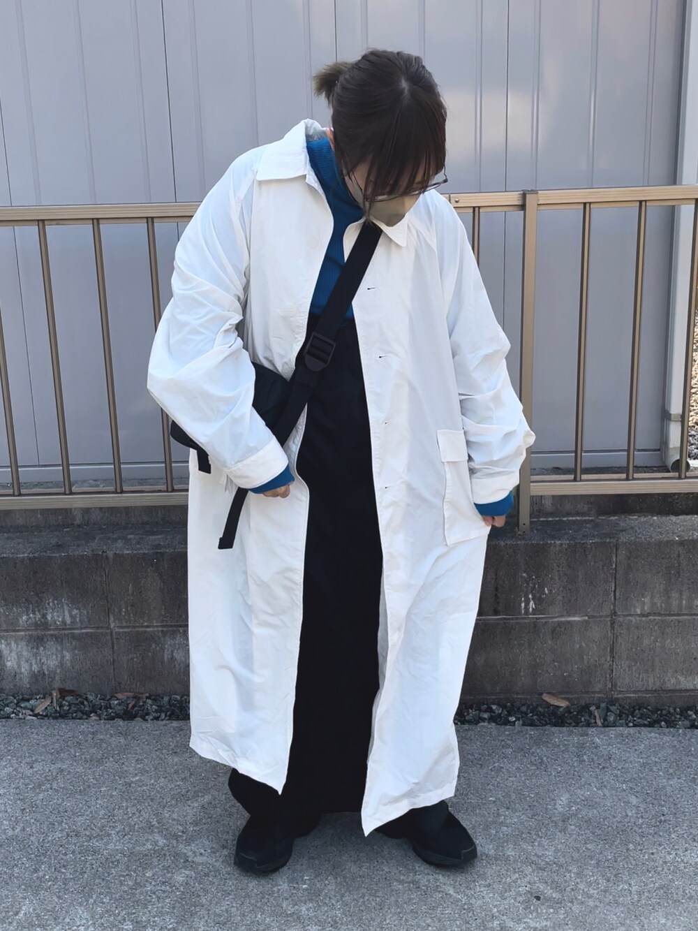 ホワイト系のステンカラーコート、ブルー系のニット/セーター、ブラック系のバッグを着用したレディースの春コーディネートの2枚目の写真