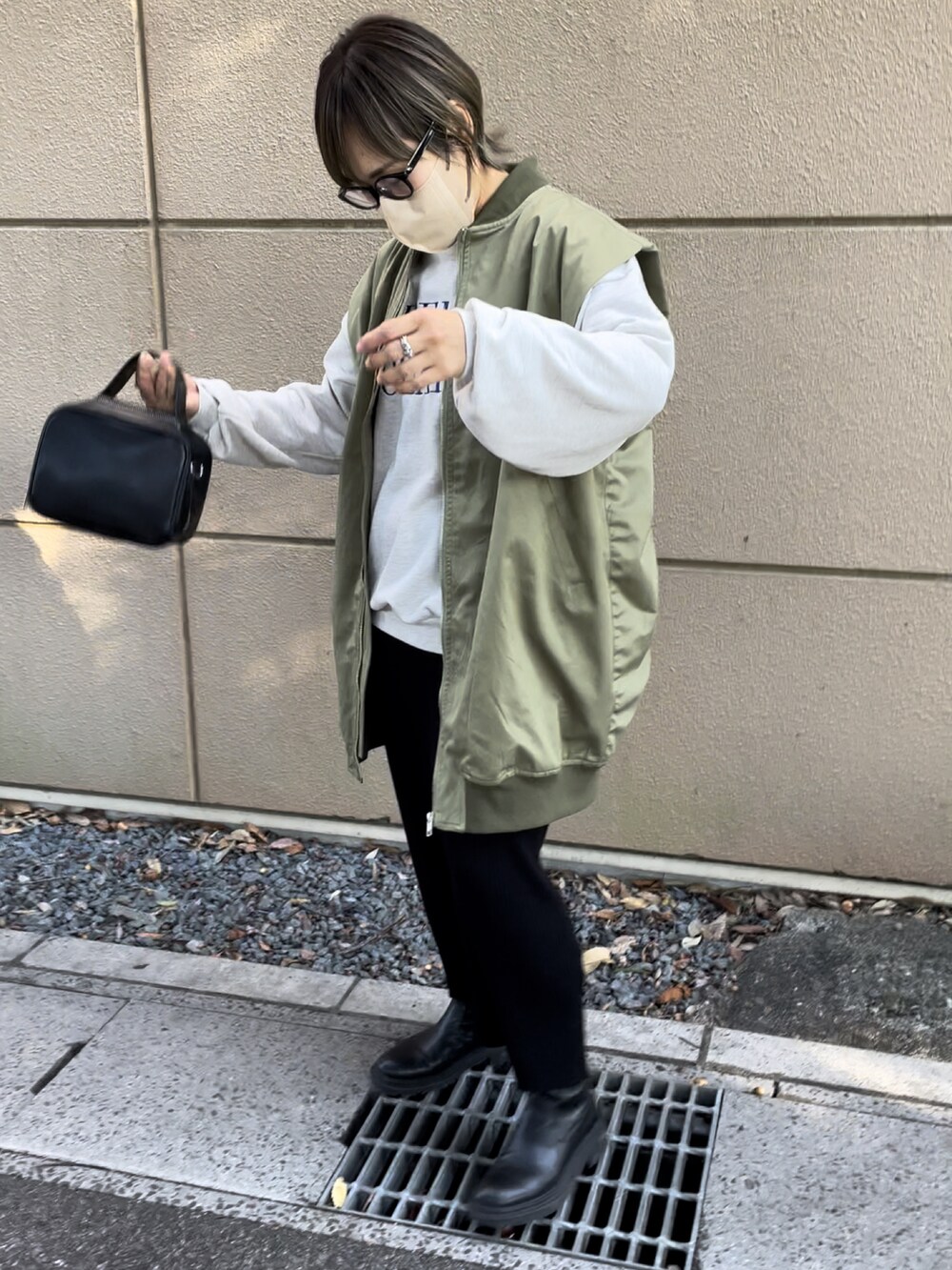 グリーン系のMA-1、ブラック系のスカート、ブラック系のボストンバッグを着用したレディースの秋コーディネートの3枚目の写真