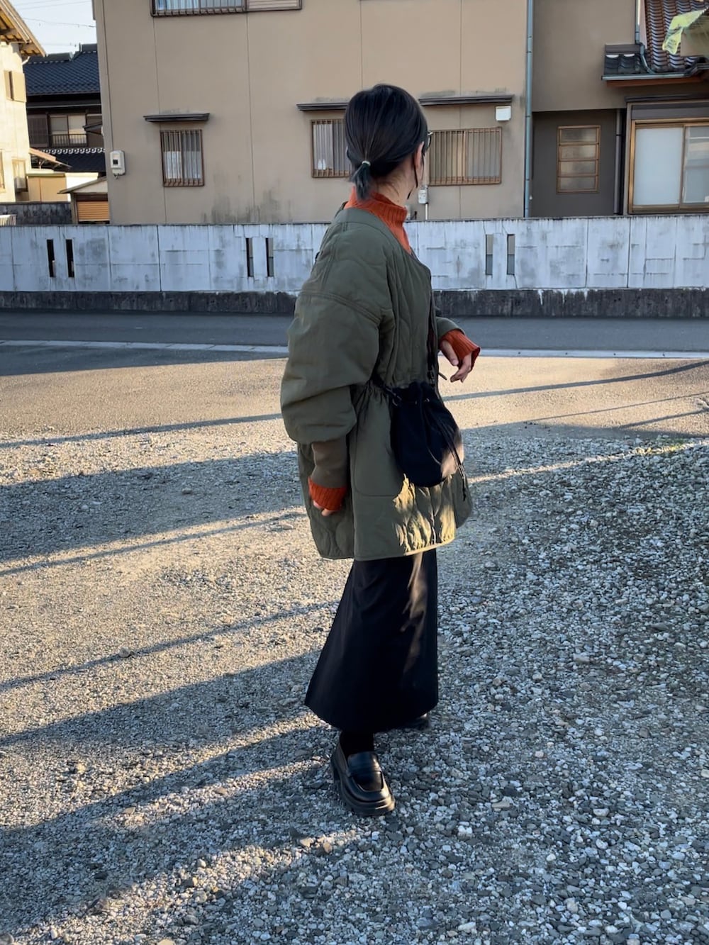 グリーン系のミリタリージャケット、ブラック系のスカート、オレンジ系のニット/セーターを着用したレディースの秋コーディネートの3枚目の写真