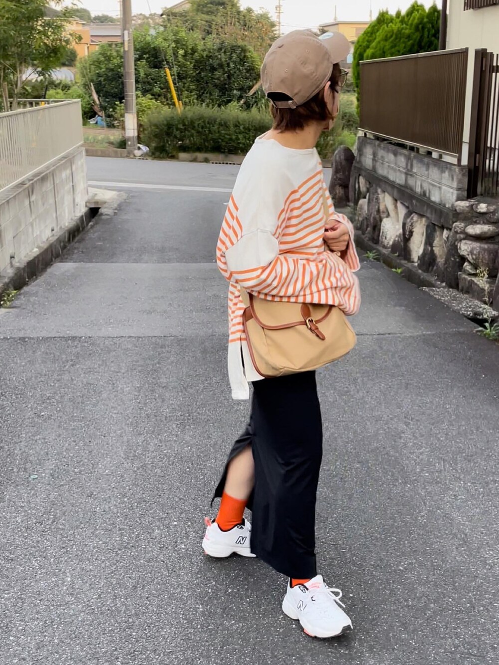 ブラック系のスカート、ホワイト系のスニーカー、オレンジ系のTシャツ/カットソーを着用したレディースの秋コーディネートの2枚目の写真