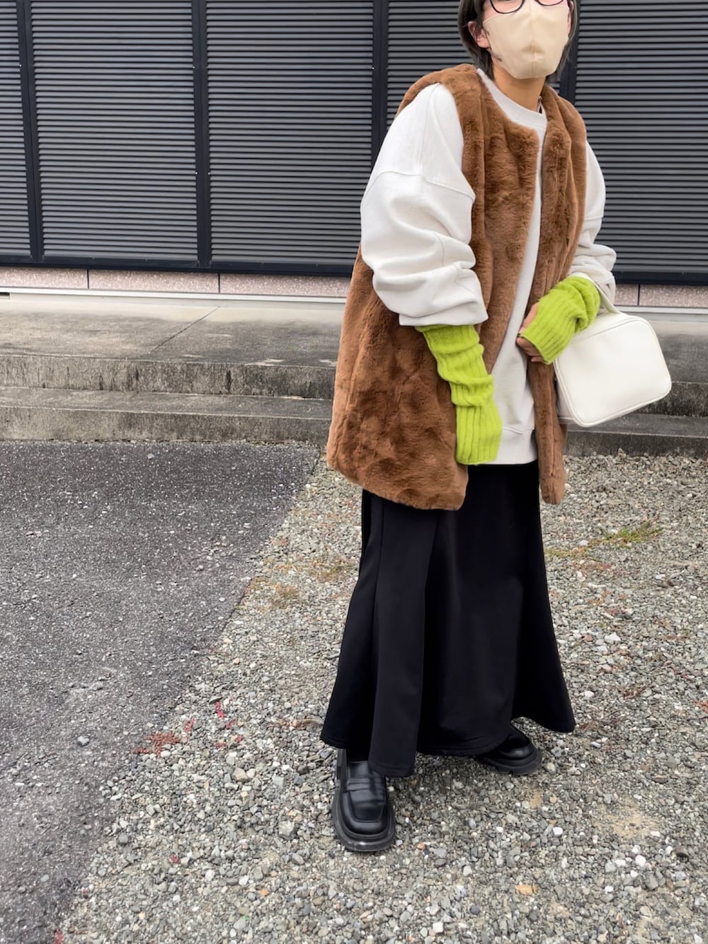 ブラウン系のベスト、ブラック系のローファー、ホワイト系のボストンバッグを着用したレディースの秋コーディネートの4枚目の写真