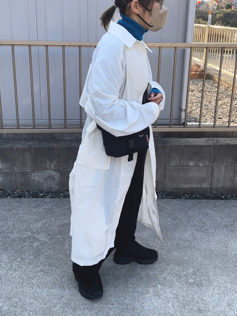 ホワイト系のステンカラーコート、ブルー系のニット/セーター、ブラック系のバッグを着用したレディースの春コーディネートの4枚目の写真