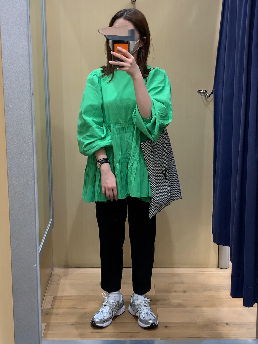 グリーン系のチュニック、ブラック系のスラックス、シルバー系のスニーカーを着用したレディースの春コーディネートの2枚目の写真