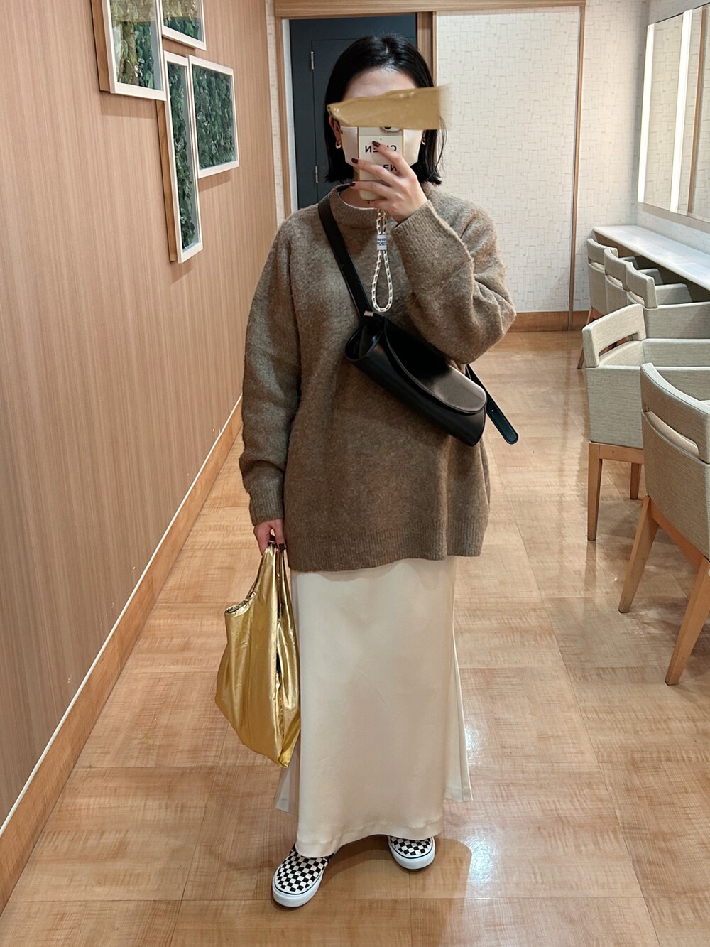 ベージュ系のニット/セーター、ホワイト系のスカート、ブラック系のショルダーバッグを着用したレディースの冬コーディネートの2枚目の写真