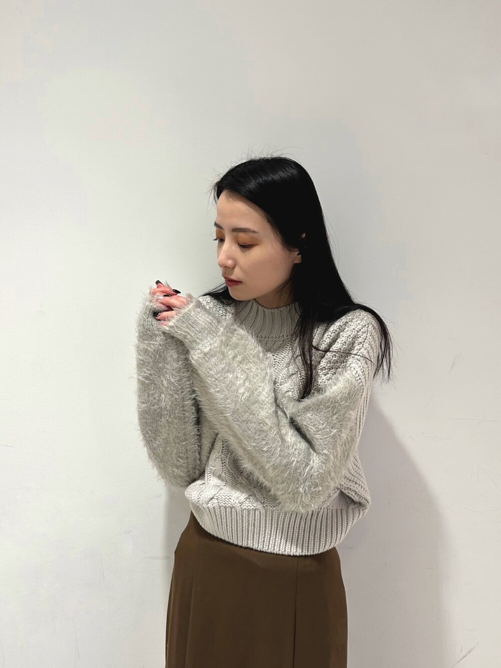 ブラウン系のスカート、グレー系のニット/セーター、ホワイト系のブーツを着用したレディースの冬コーディネートの4枚目の写真