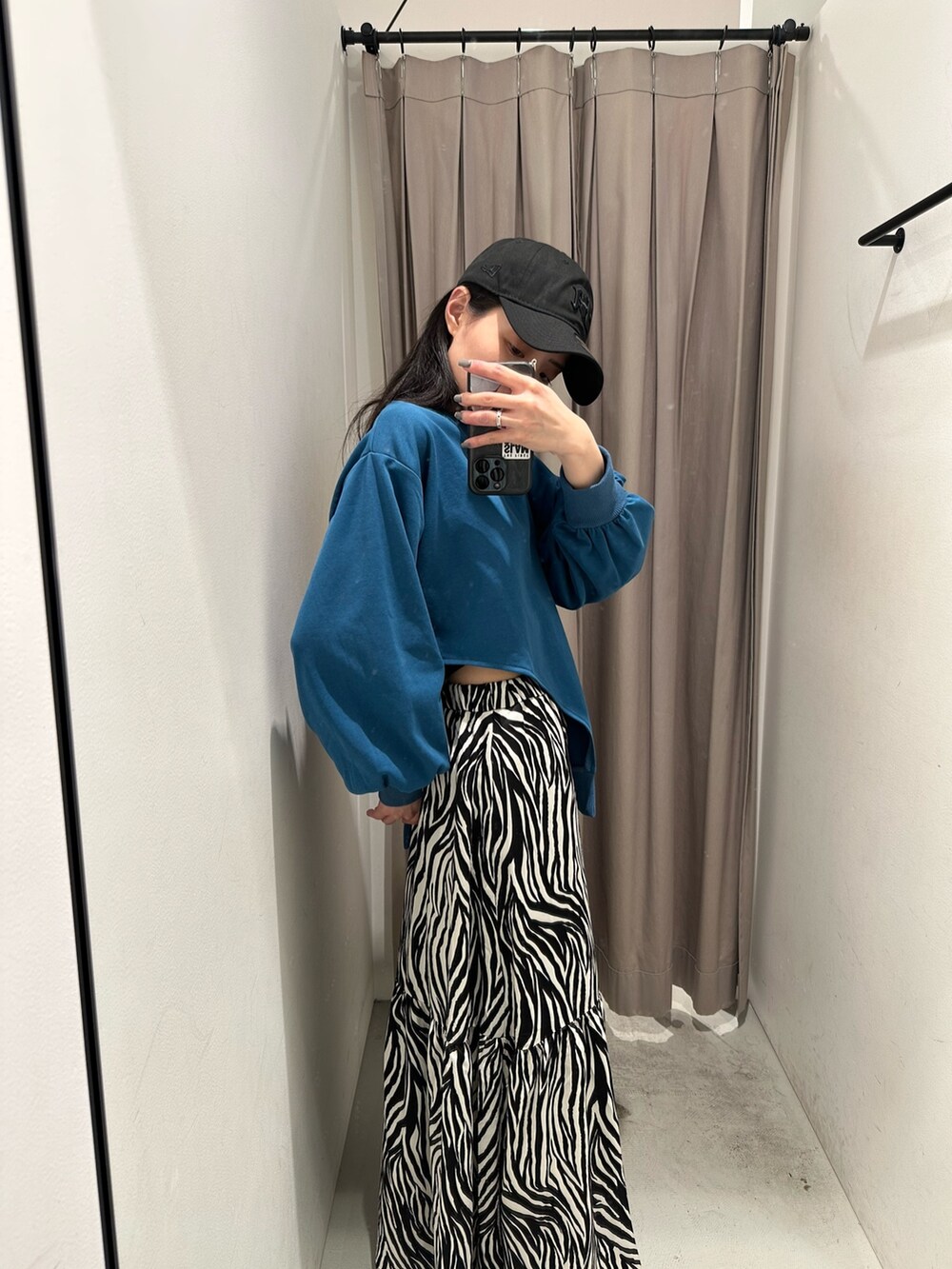 ブルー系のTシャツ/カットソー、ホワイト系のスカート、ブラック系のキャップを着用したレディースの春コーディネートの6枚目の写真